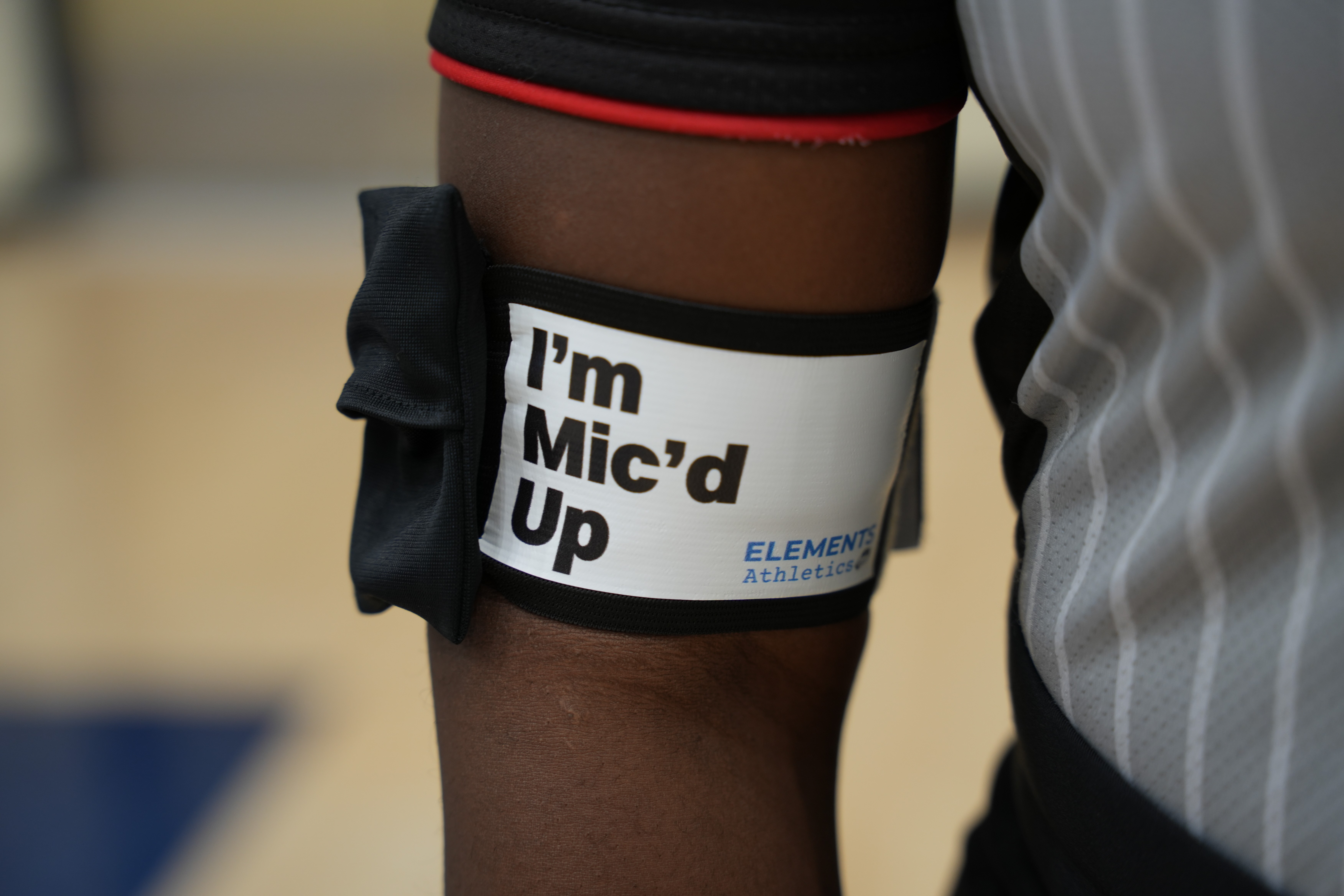 person wearing the mic'd up armband and mic referring a baskeketball game