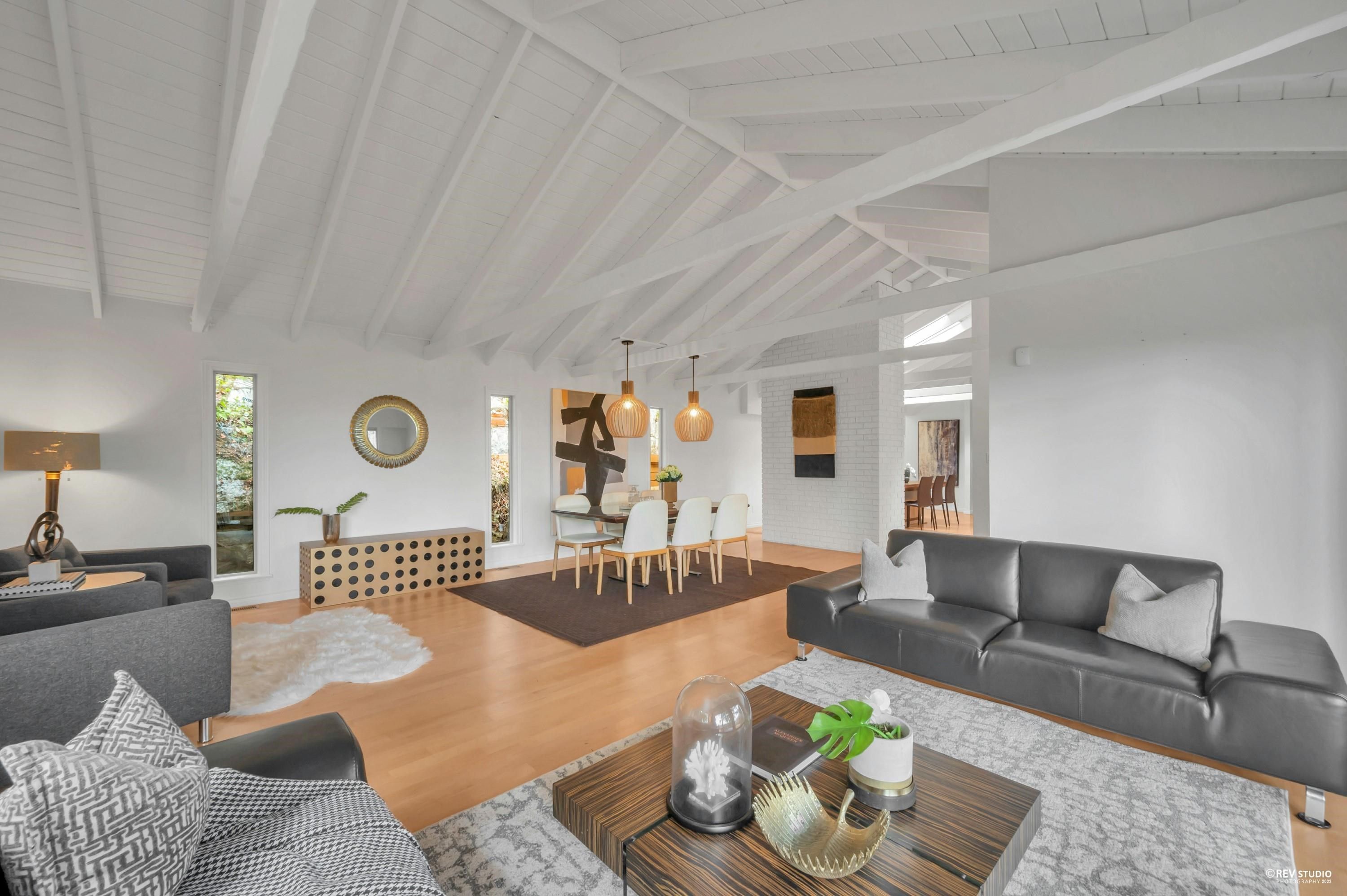 Modern living room with a light color palette, wooden furniture, plants, and an open layout featuring cozy decor.