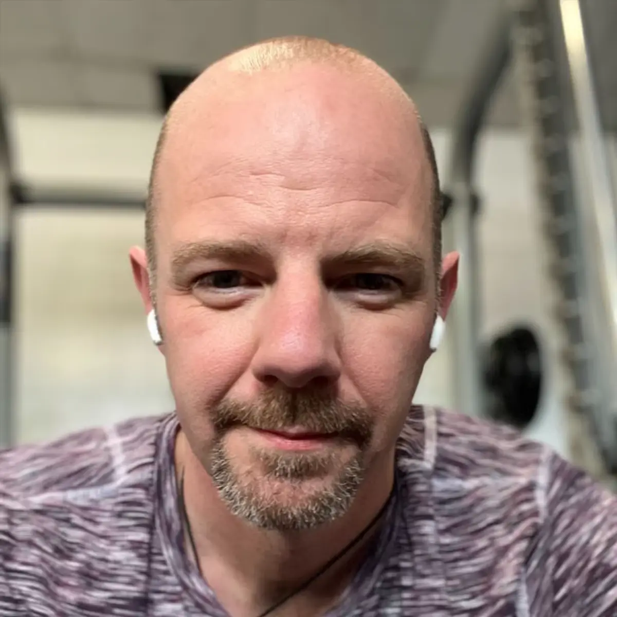 Portrait of a man at the gym wearing earphones, taken during a workout break.
