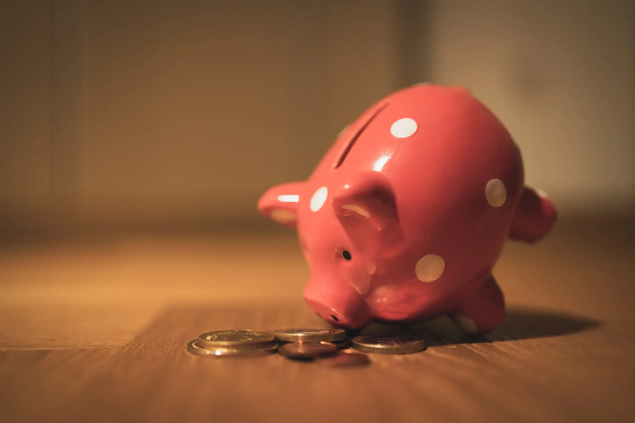 A piggy bank with gold coins on the floor around it