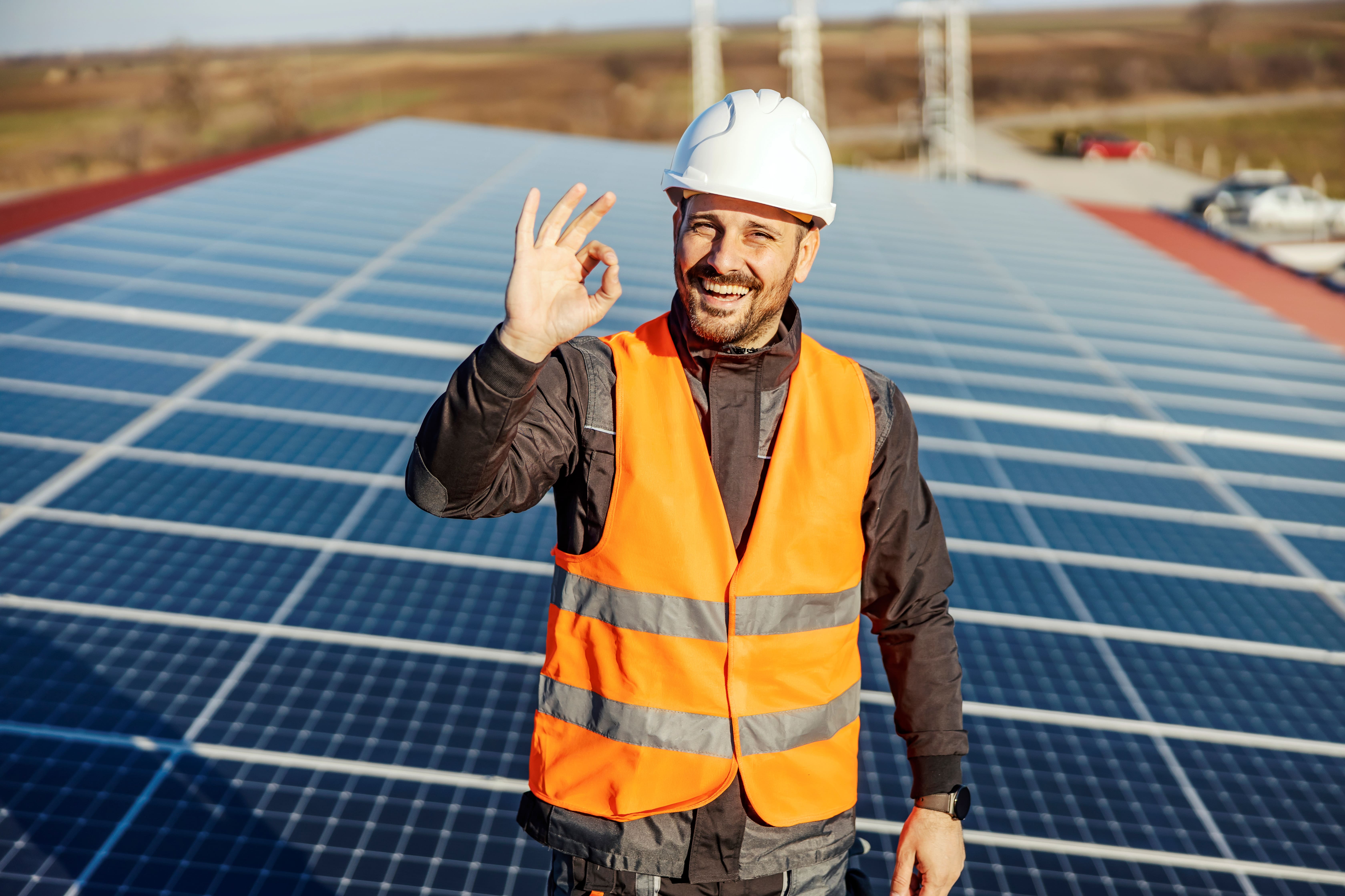 Zufriedener Solarteur mit Schutzhelm und Warnweste vor großflächiger Photovoltaikanlage – Arbeiten bei Solartechnik Nordwest im zukunftssicheren Solarhandwerk.