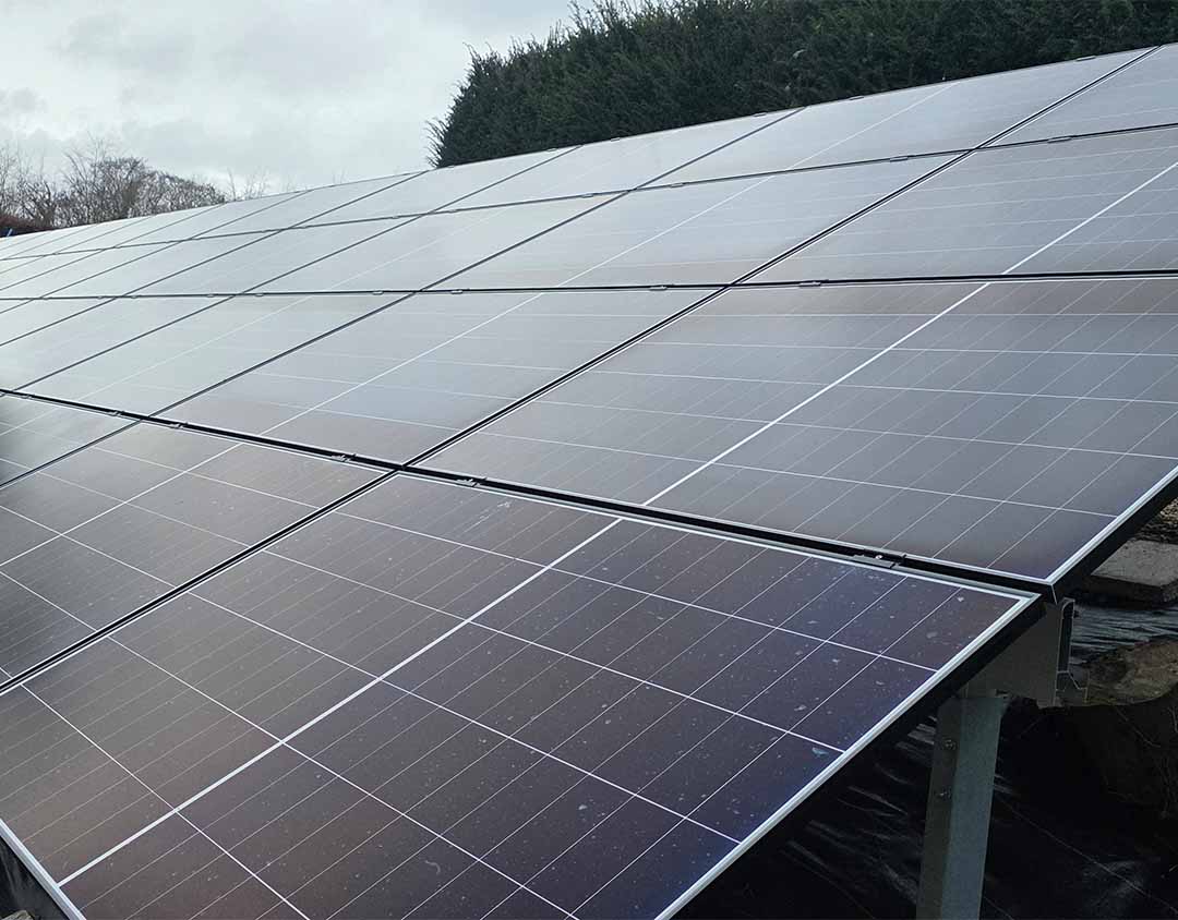 Close-up of high-efficiency solar panels mounted on a custom steel racking system on a south-facing embankment.