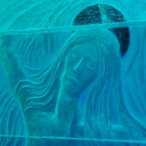 An intricate ice carving of a serene woman with long hair and a halo-like circle behind her head in a blue tint.