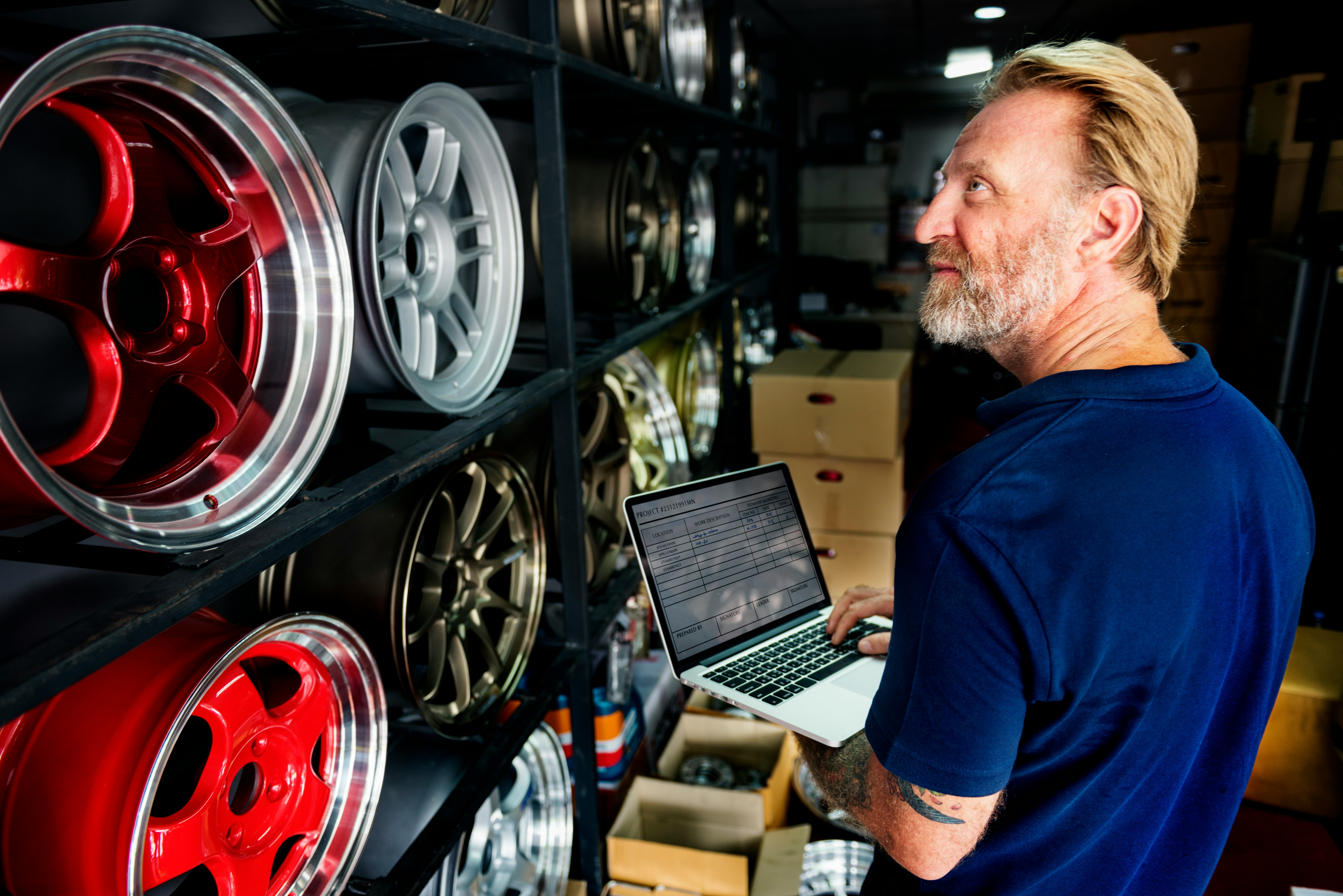 man with laptop looking at a all of alloy wheels