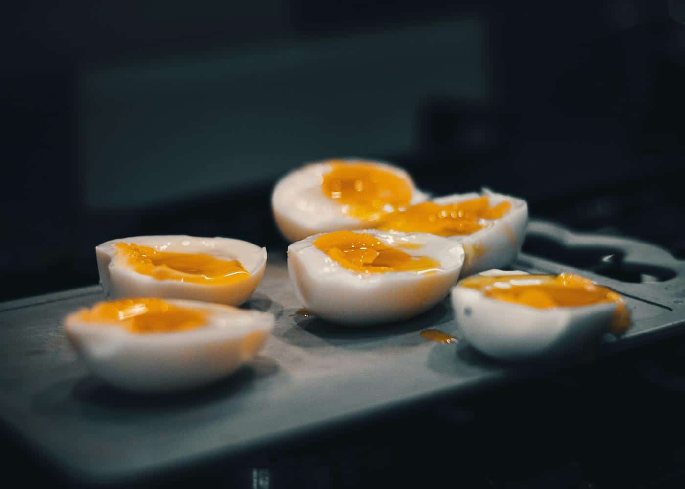 Soft boiled eggs cut in half showing runny yolk sitting on top of a black cutting board
