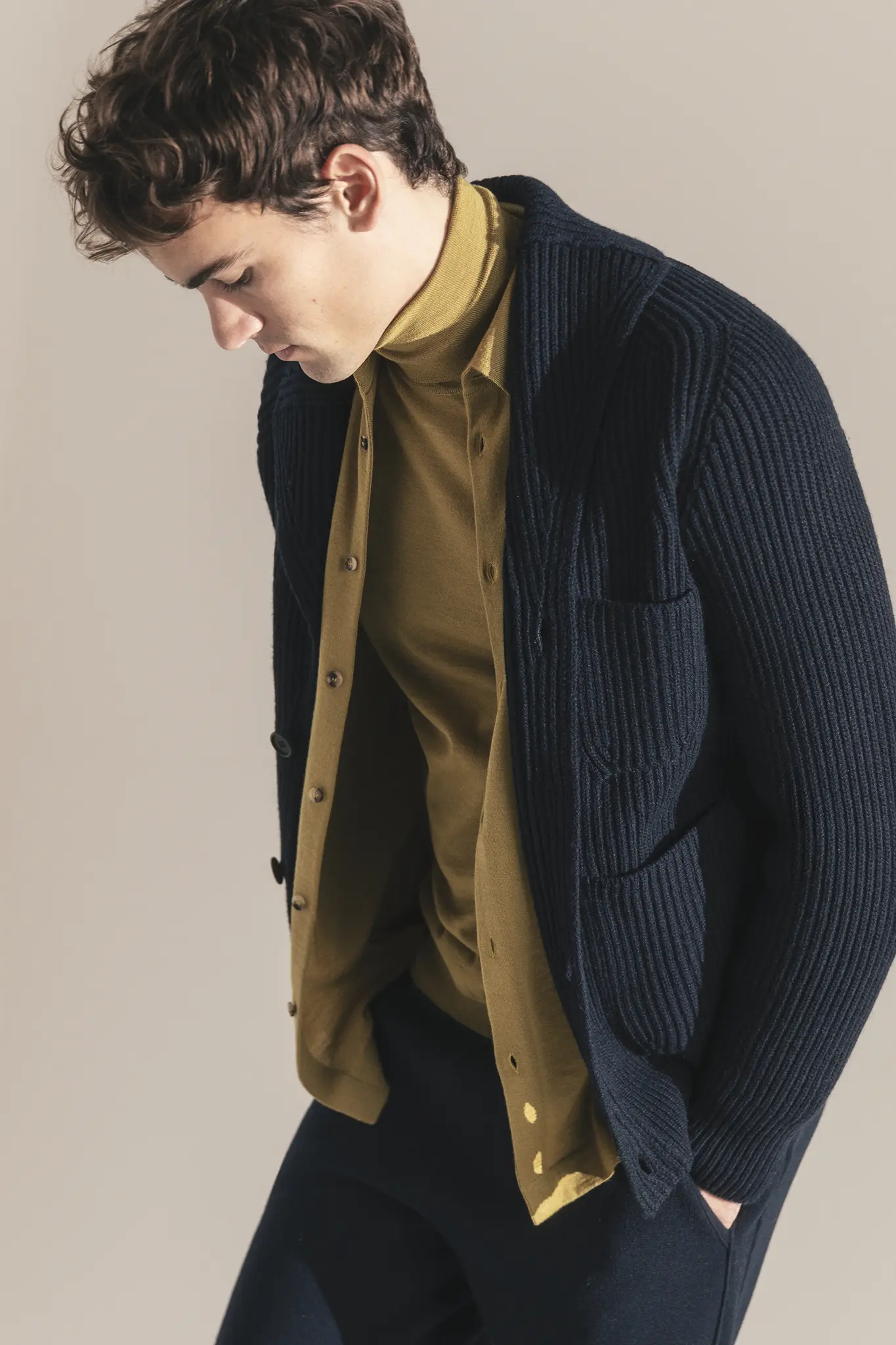 Man in navy ribbed cashmere cardigan layered over mustard turtleneck and shirt – Aida Barni FW25/26 collection.