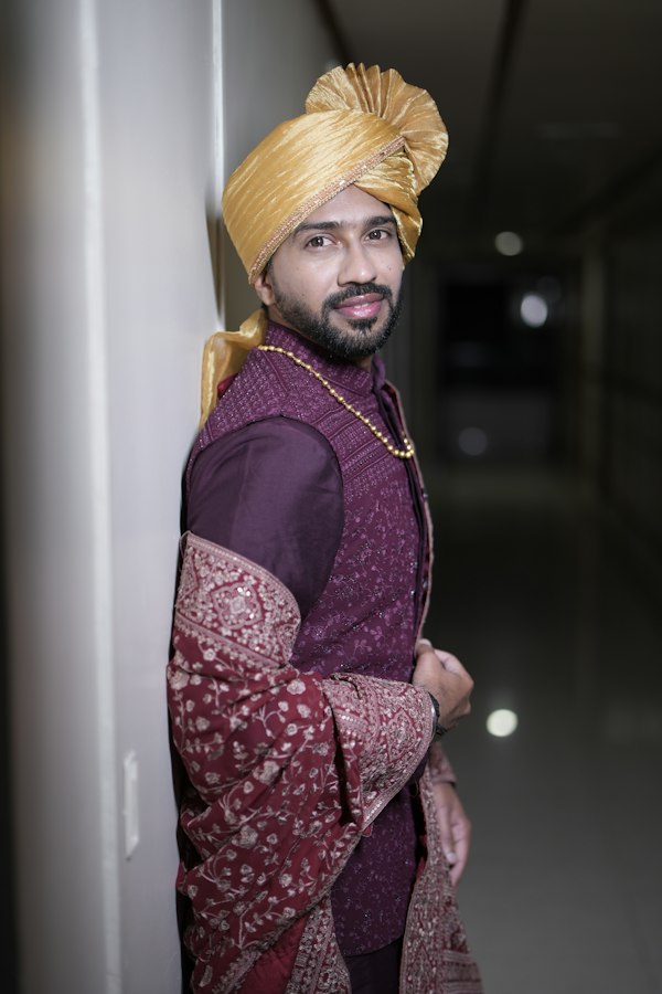 Smiling groom in a golden turban and maroon sherwani