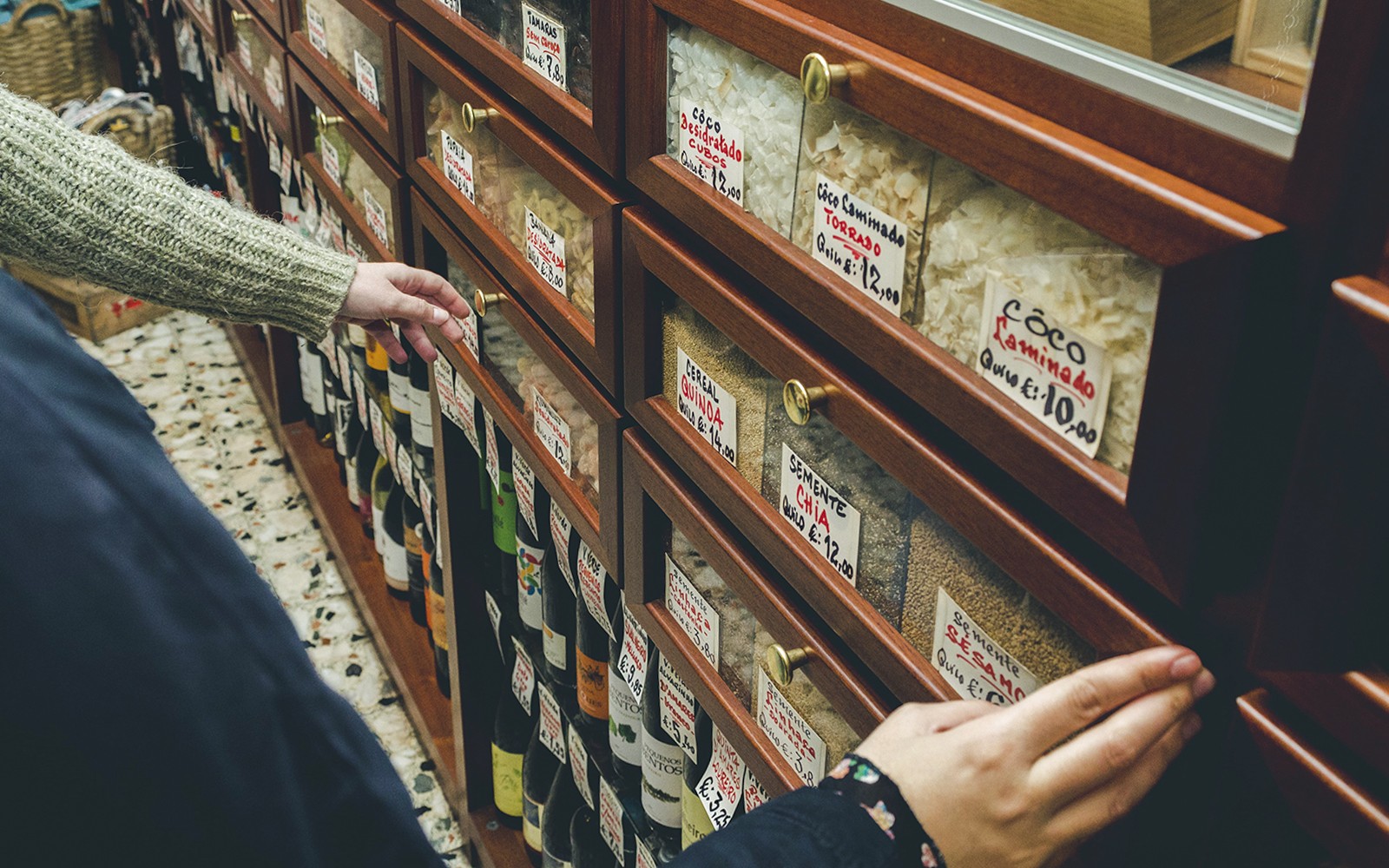 在葡萄牙的美食商店中,手從貨架上選擇物品,進行品酒之旅。
