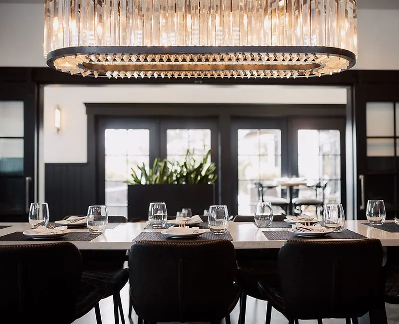 Pain d'Avignon private dining room — elegant rectangular table set for guests beneath a crystal chandelier