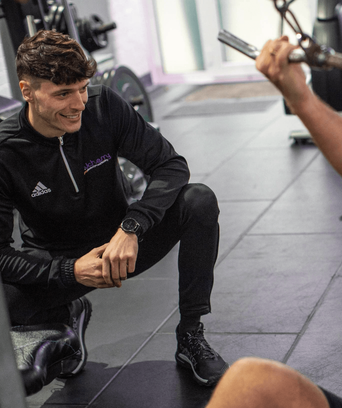 A personal coach is smiling with his arms crossed, wearing a black