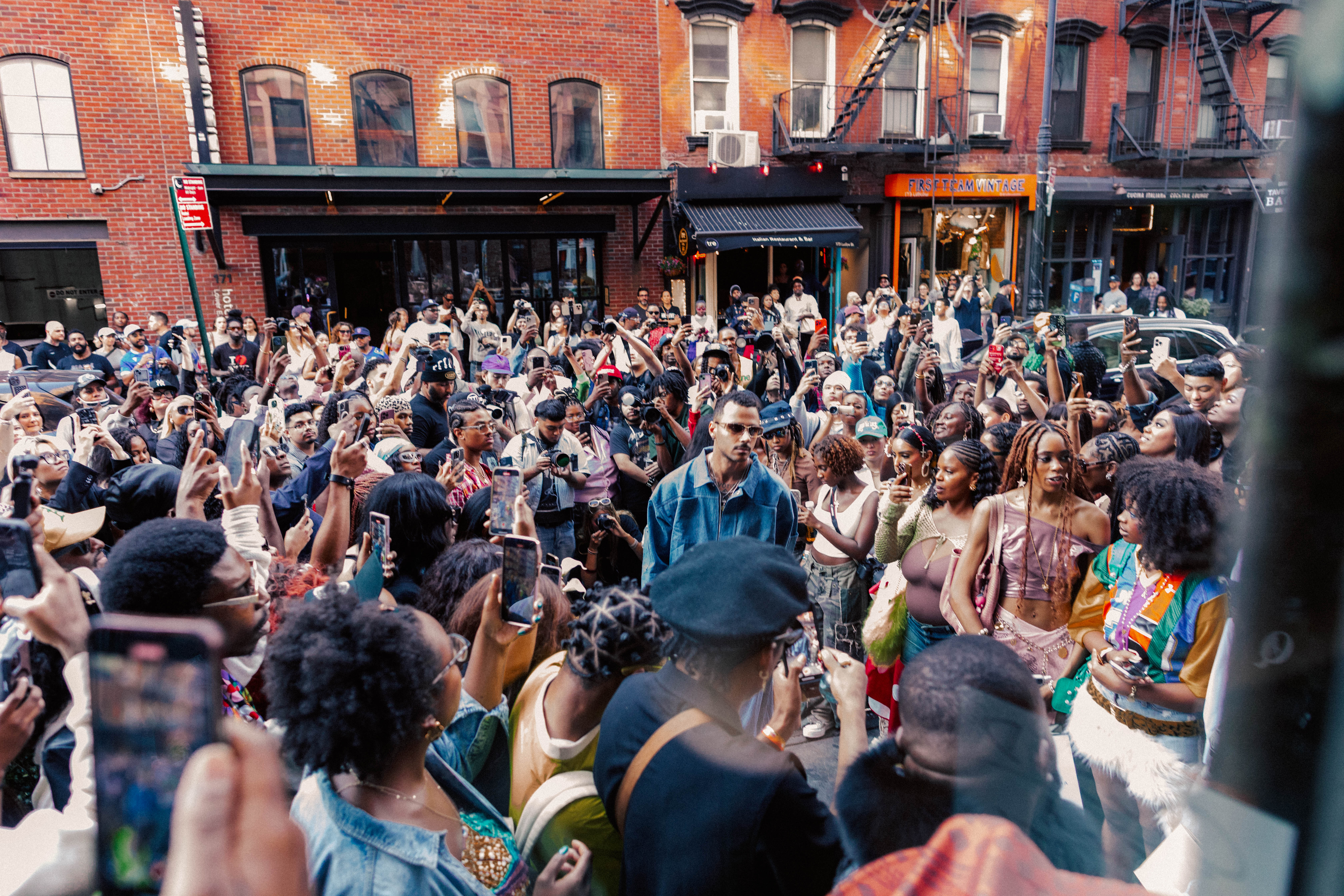 Crowd gathered outside a KEEMSTUDIOS NYFW event, phones up, capturing the moment on a city street.