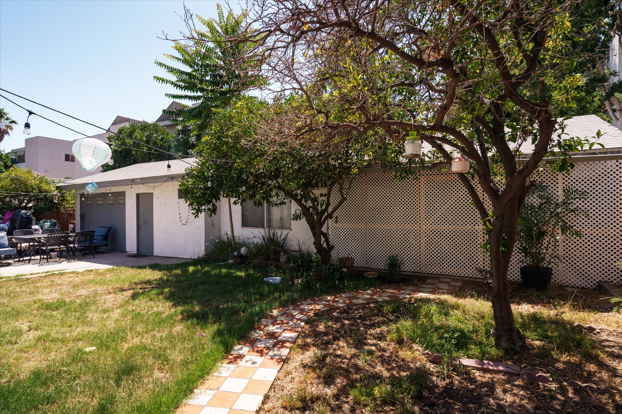 A back house at 1807 n van ness, with a light exterior, surrounded by green grass and trees under a clear blue sky.