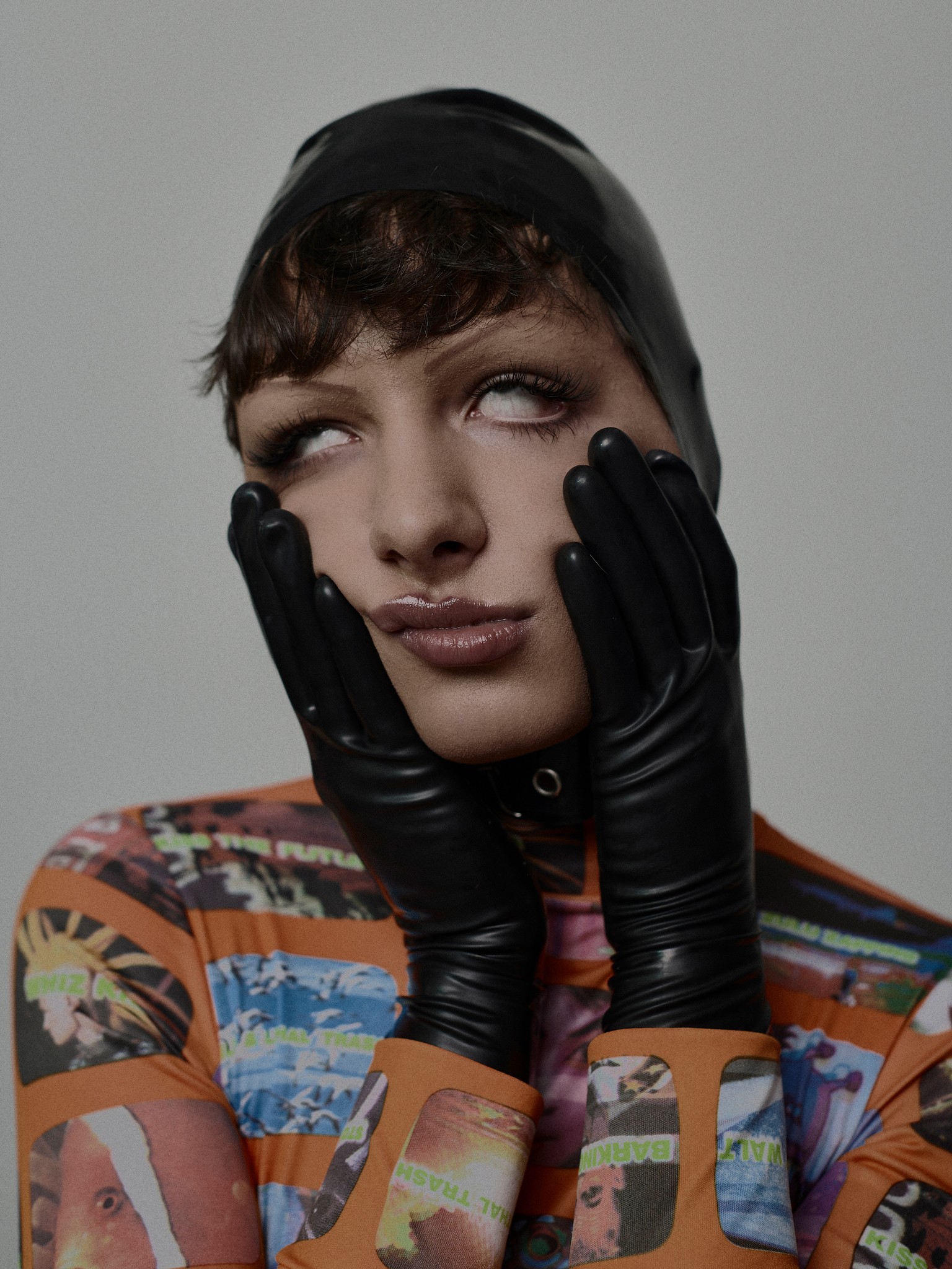 An editorial portrait of a young person, wearing a walter van beirendonck ‘tv trash’ top, latex gloves and head piece. The subject is in an expressive, exacerbated pose, with eyes rolled back. Shot in the photo studio in New Orleans, LA. 