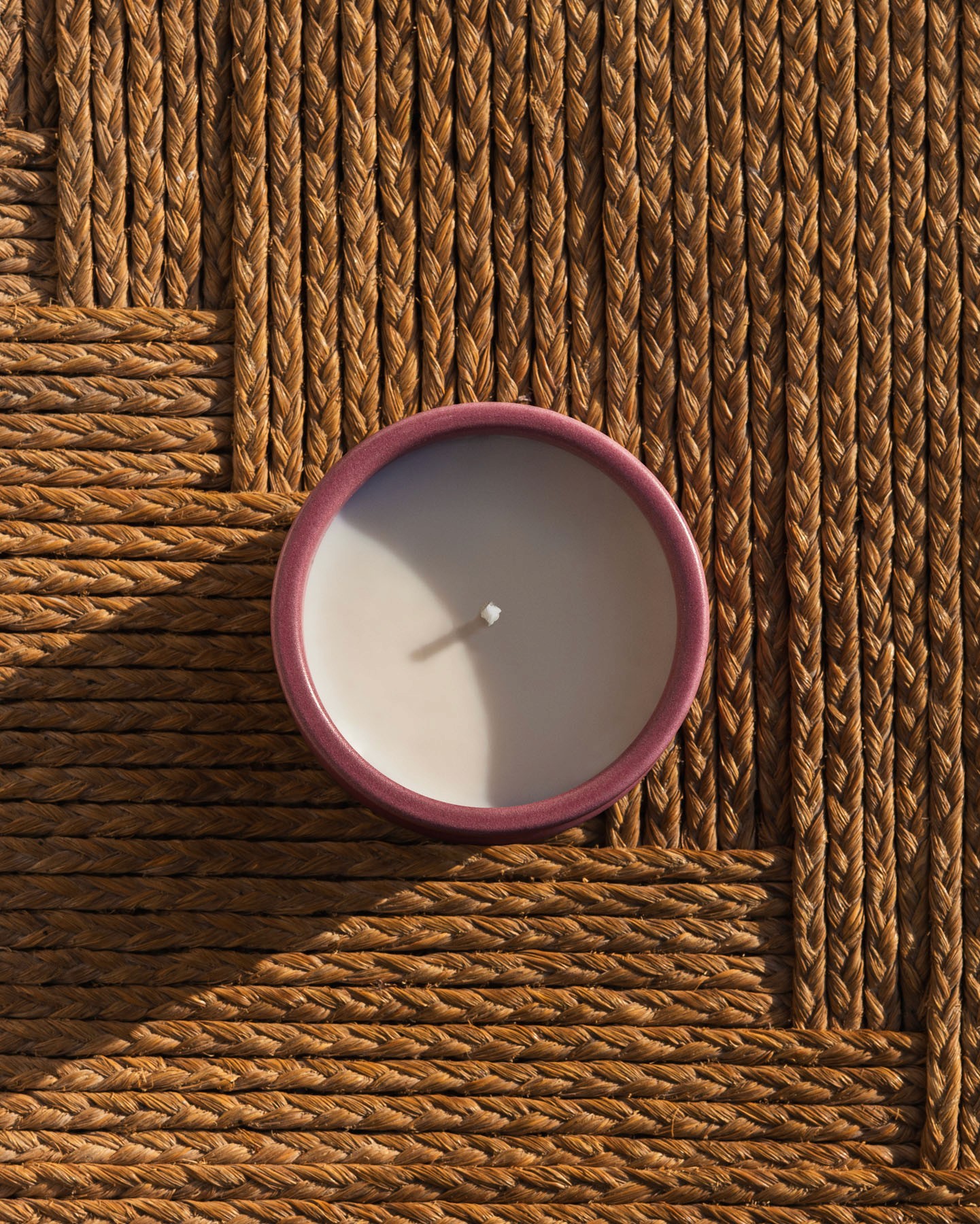 Ivy LOEWE Home Scents candle placed on a woven natural-fibre surface.