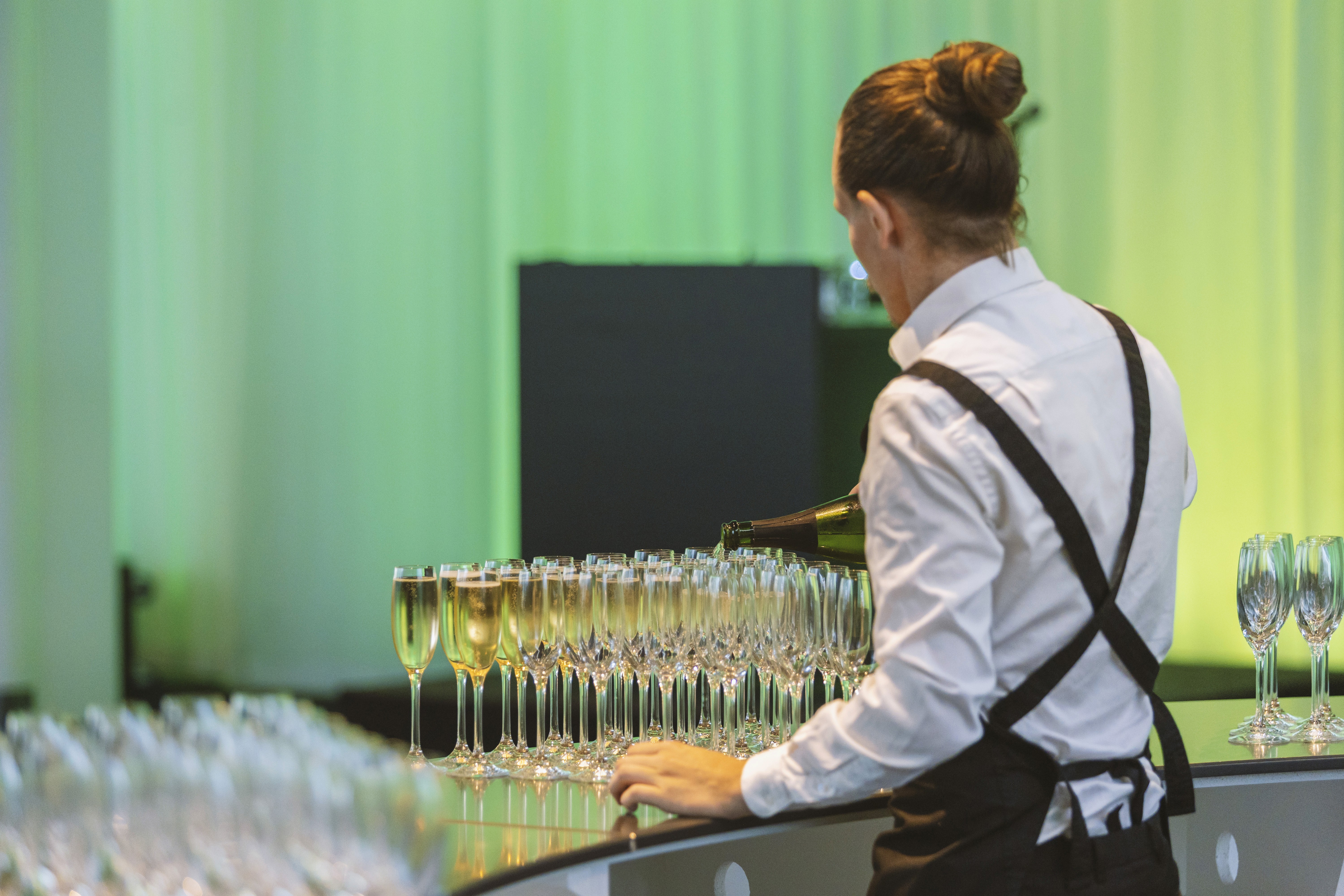 En servitör som häller mousserande vin i champagneglas