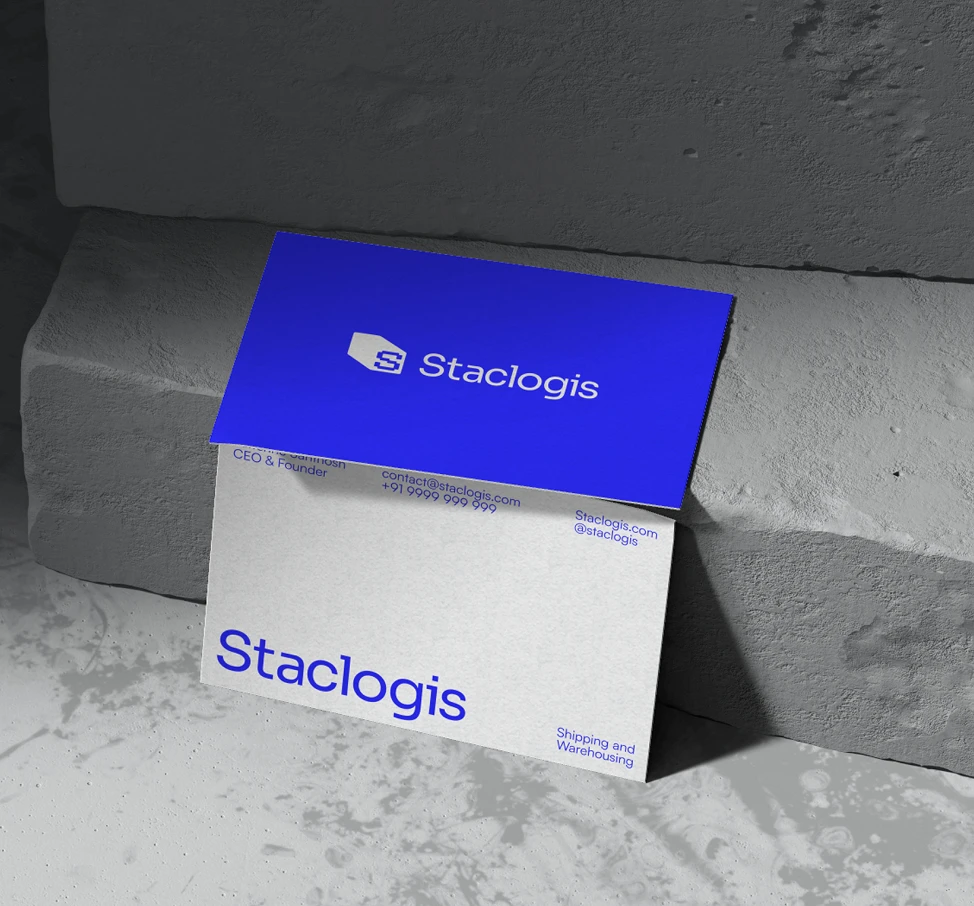 Blue and white Staclogis business cards propped against grey concrete blocks.