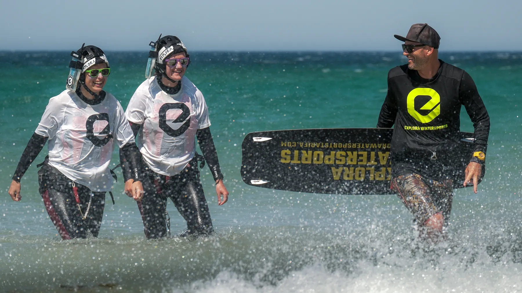 Kitesurfing-Unterricht in Tarifa mit einem Instruktor von Explora Watersports und Schülern, die aus dem Meer kommen.