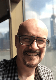 a man with a goatee smiles at the camera