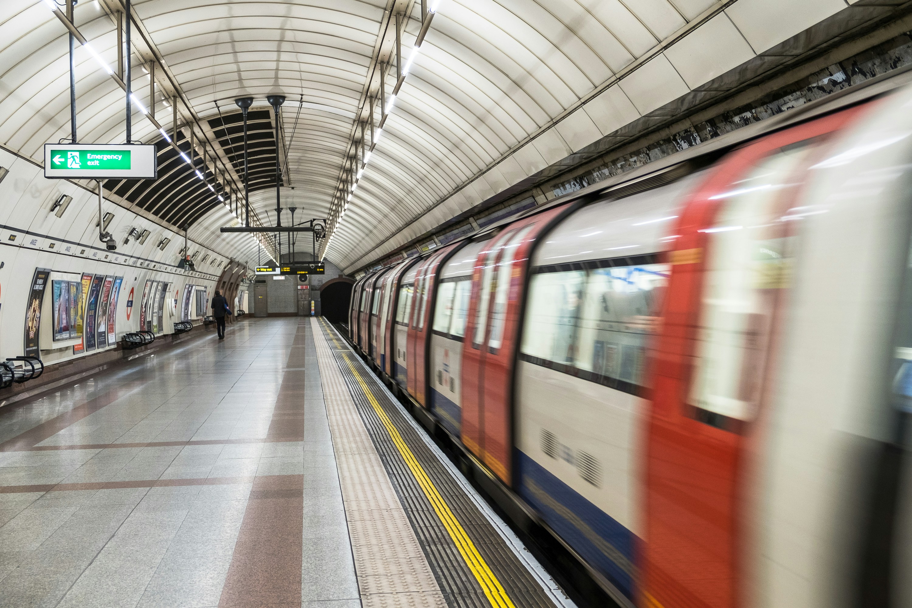 A London underground station, with a train blurred train passing by.