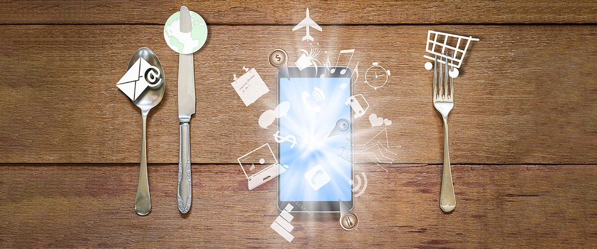 Four vintage silver utensils are arranged on a wooden surface, reflecting light in an artistic display.