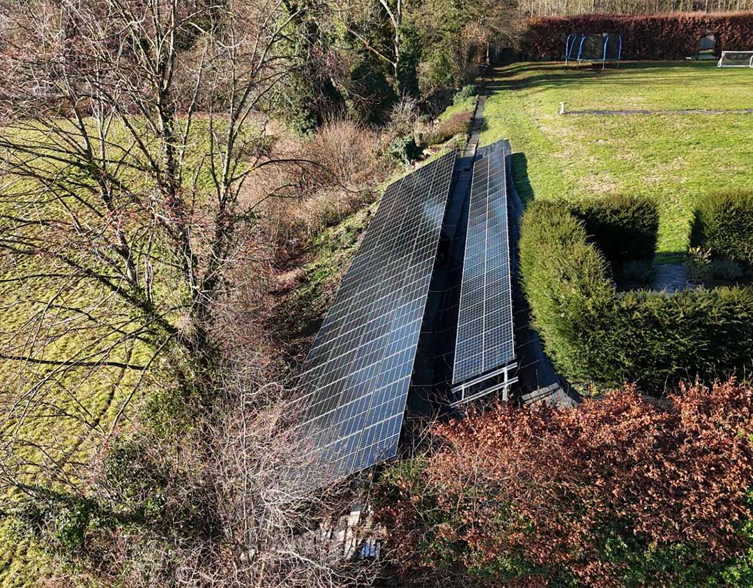 Side view of ground-mounted solar panels installed on a steep embankment using screw pile foundations in Puttenham, Surrey.