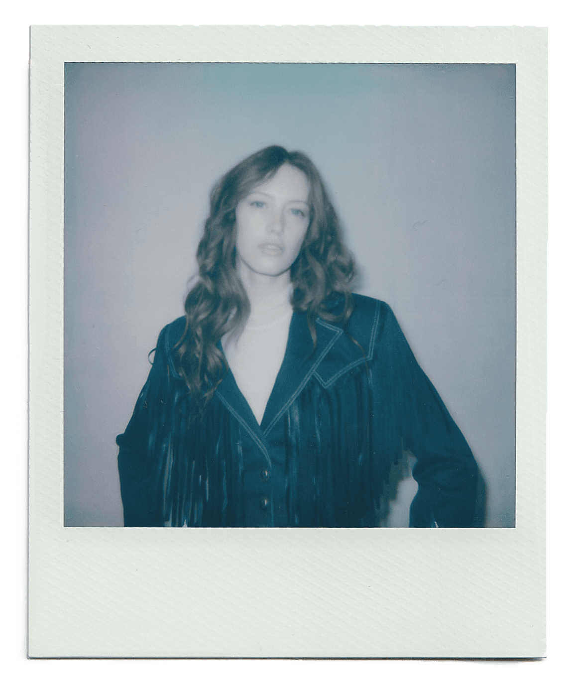 A tan sighthound stands in a grassy field.