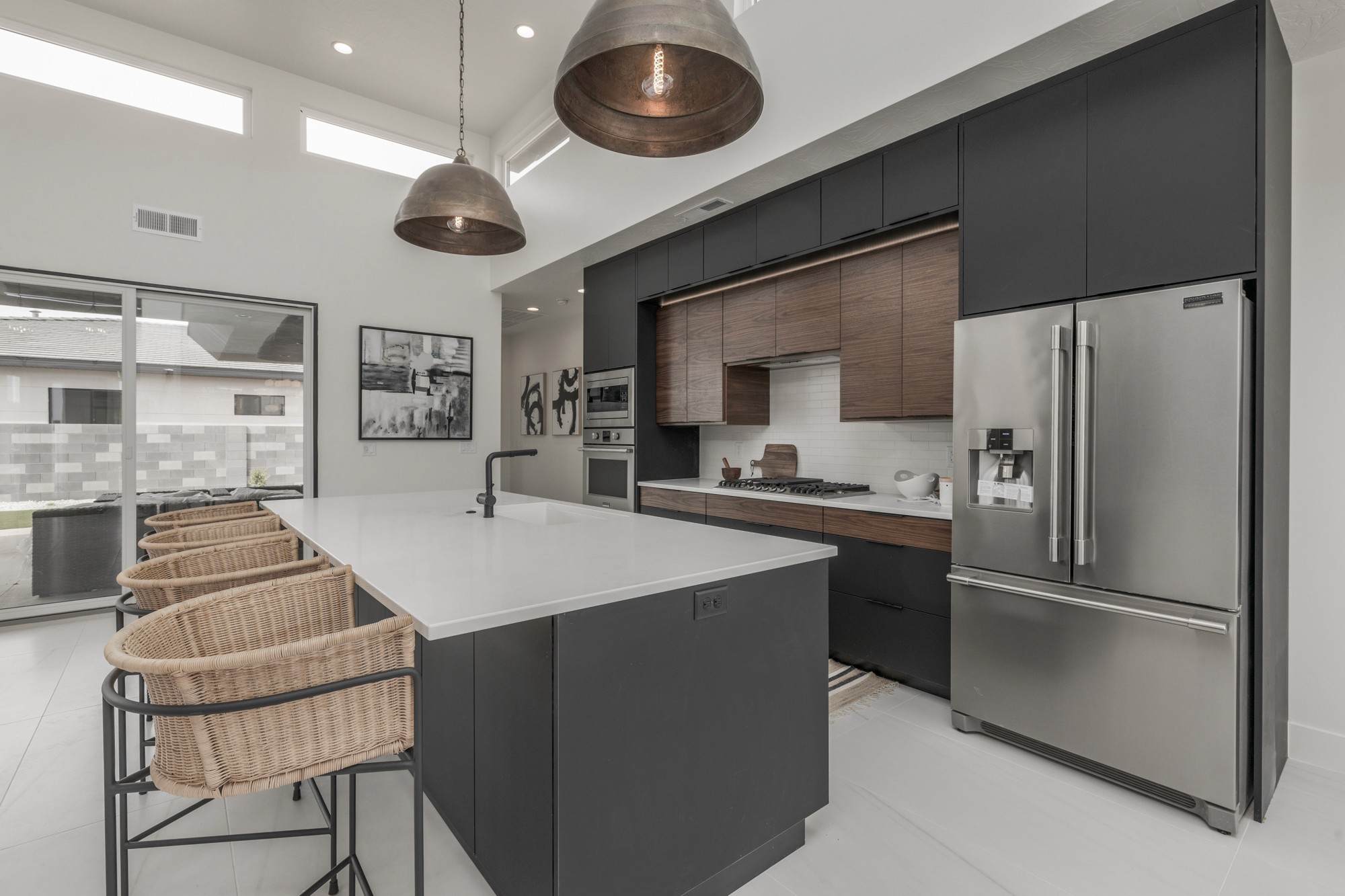 Modern kitchen in a custom home in Hurricane, Utah with painted cabinetry and wood tone flat panel cabinetry, custom light fixtures, and an open concept living space.