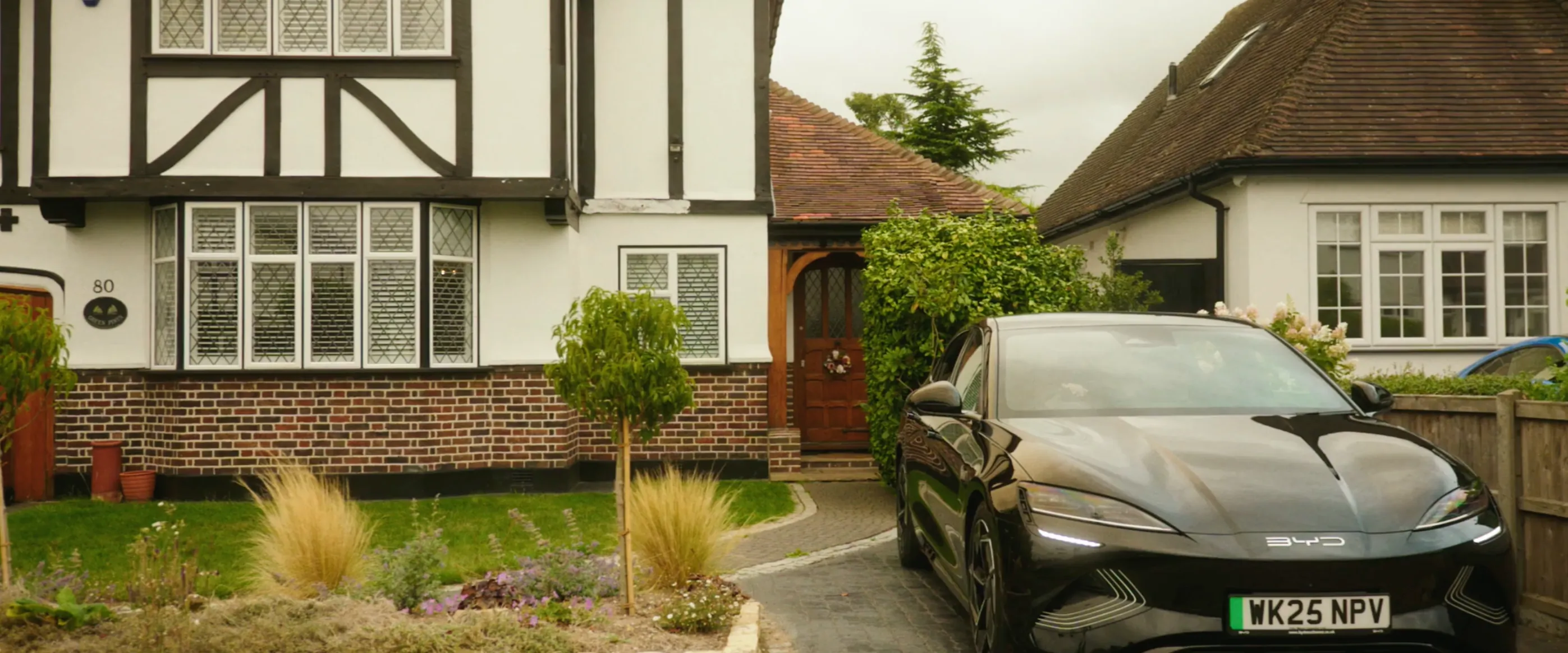 A black car parked in the driveway of a large house