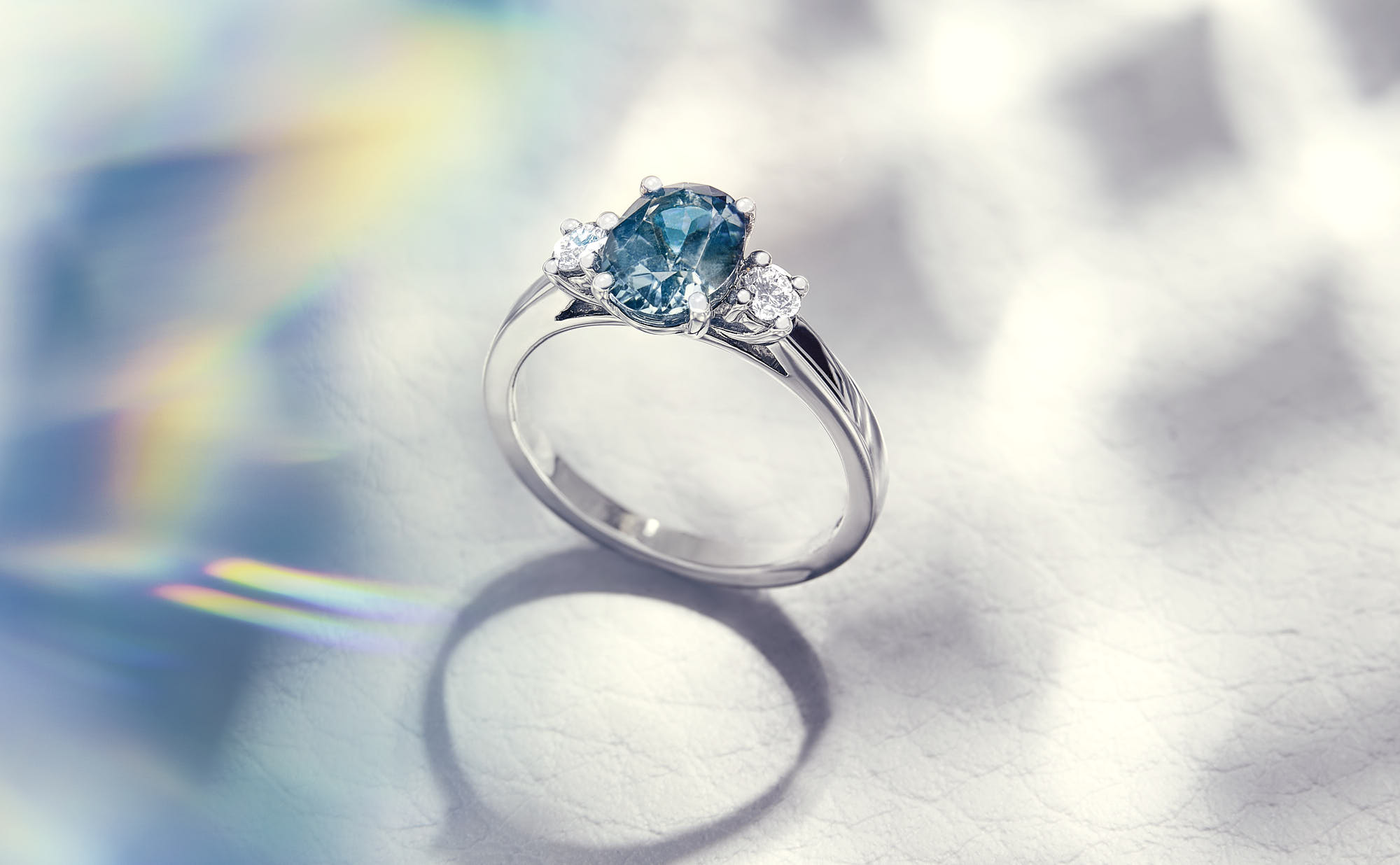 Elegant silver ring with a blue gemstone and two diamonds, luxury jewelry.