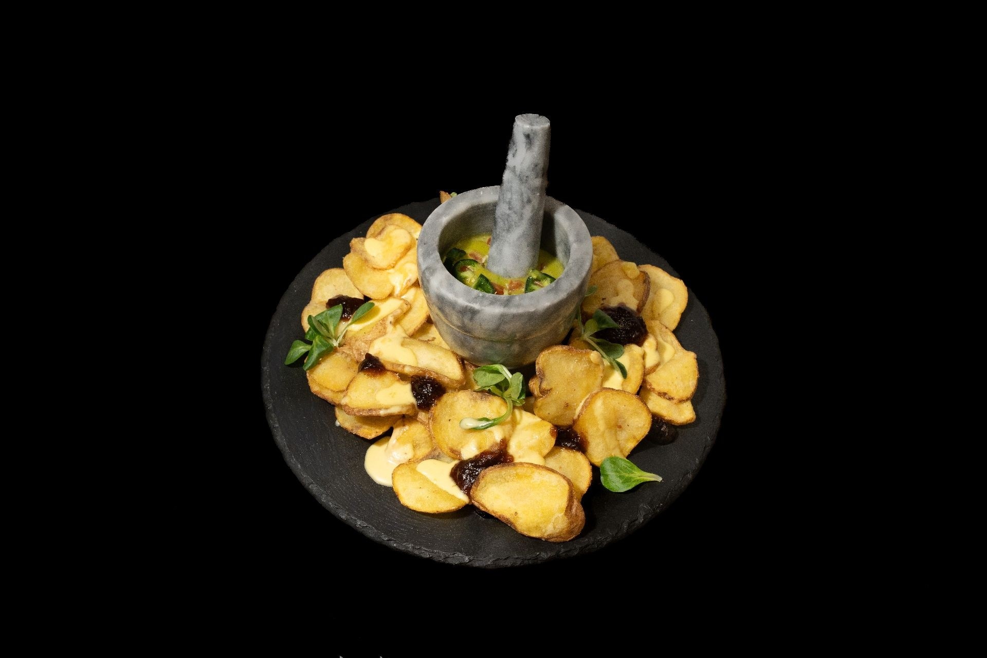 Patate croccanti con composta di cipolle, crema al Parmigiano e con salsa avocado servita in pestello di pietra su vassoio di ardesia nero