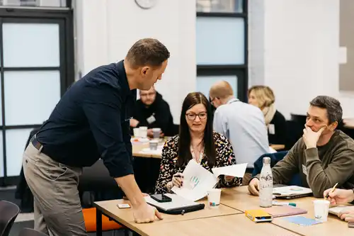People sitting at a table, one working on papers.