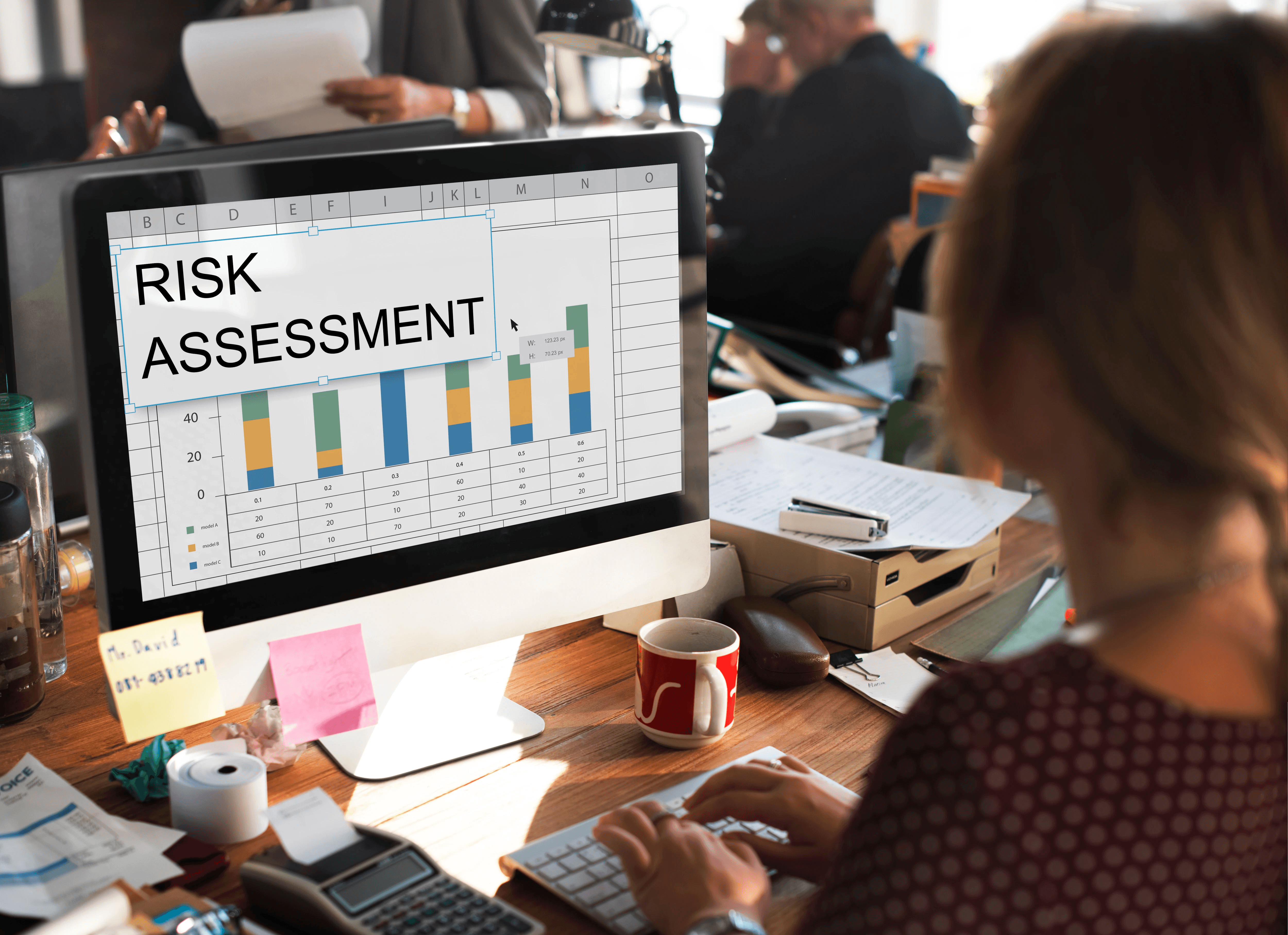 A person sits at a desk, viewing a computer screen displaying colorful bar graphs related to advertisement data.