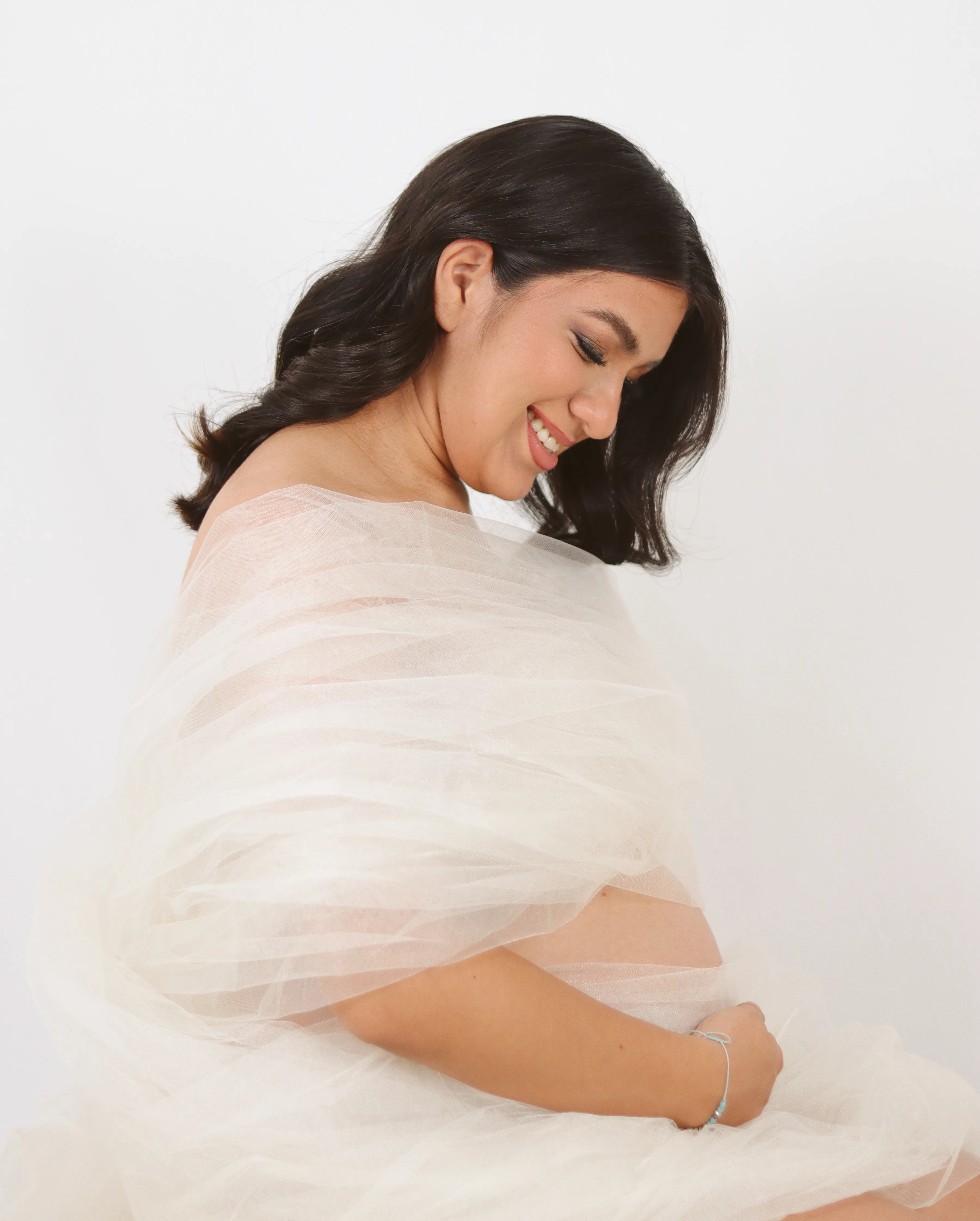Retrato de maternidad con madre sonriendo mientras toca su vientre