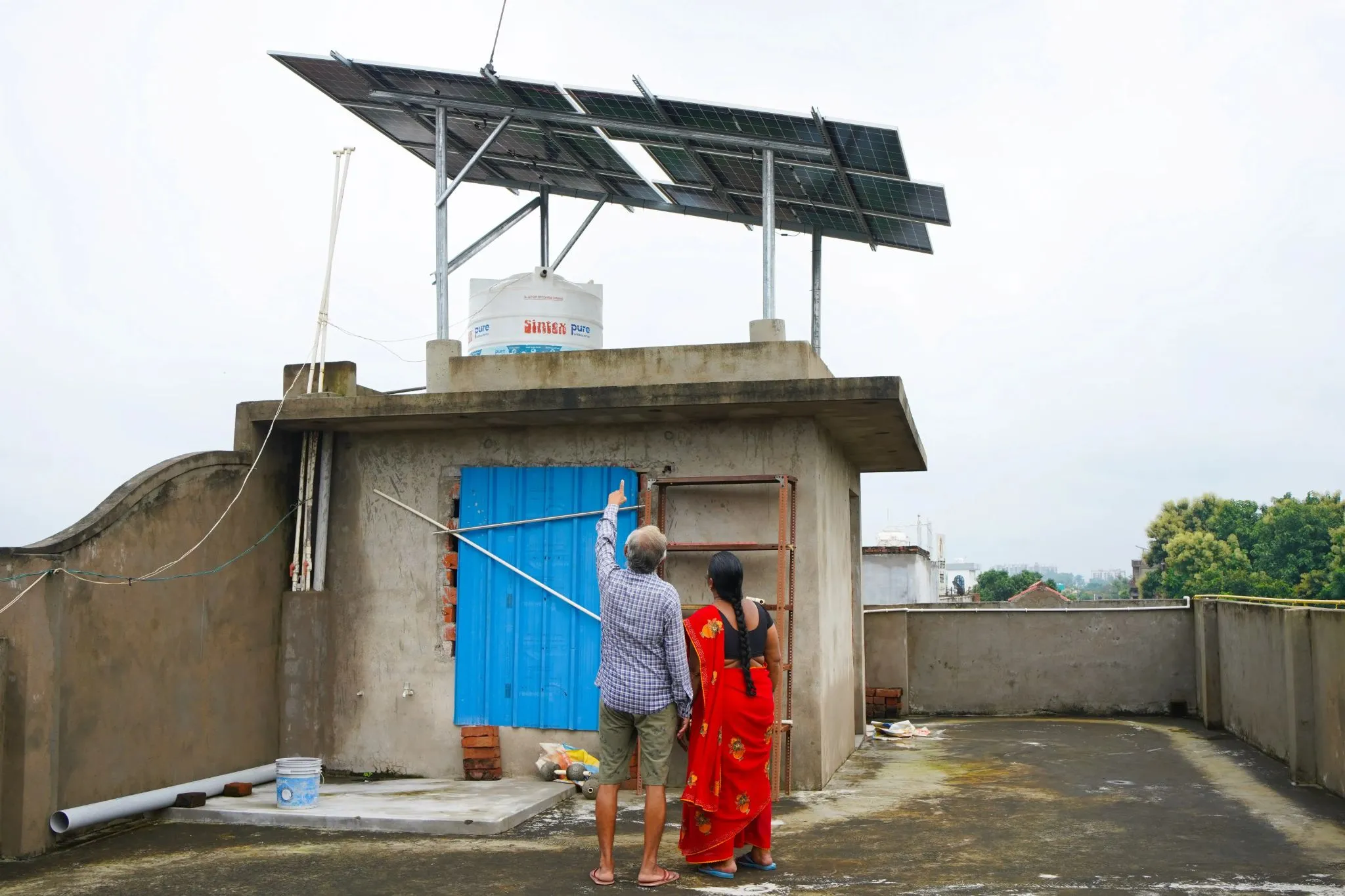Woman in a red sari on a rooftop beneath an elevated solar panel structure