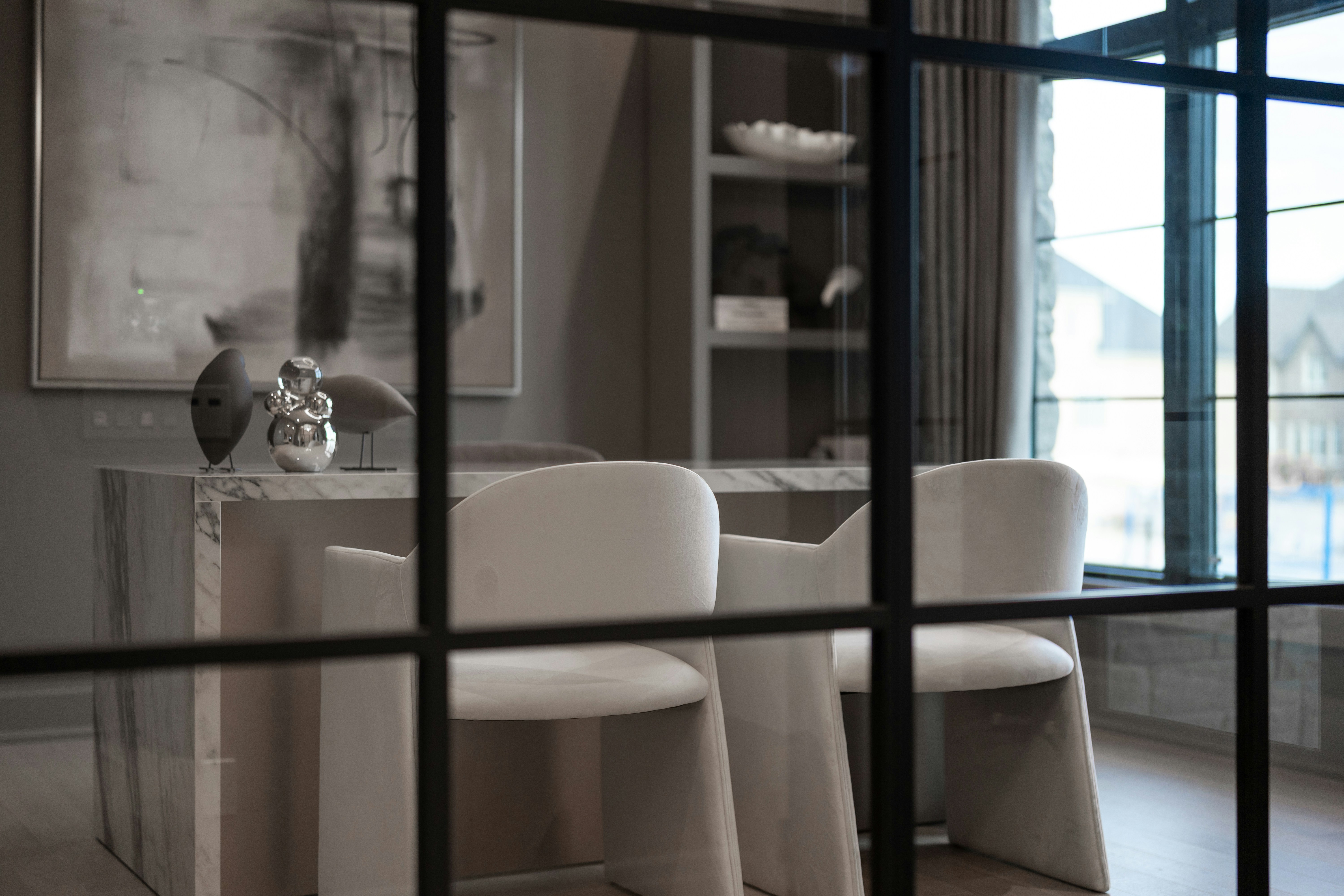 Elegant office interior with white chairs behind a grid window.