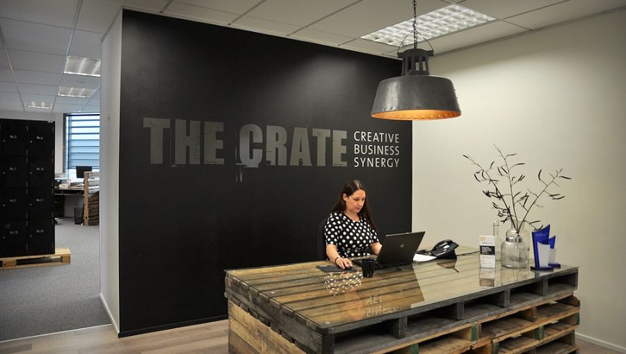 Receptionist busy working on her laptop behind the reception desk at The Crate Hamilton.