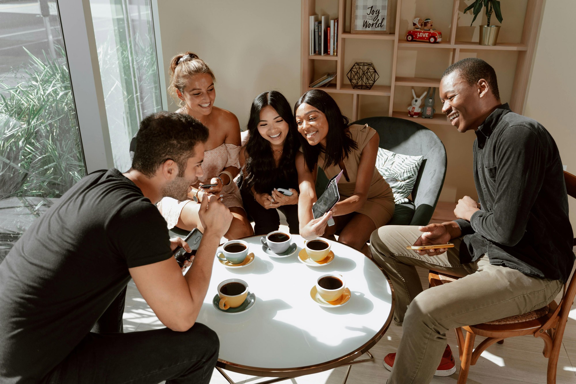 Group of friends gathered around table drinking coffee