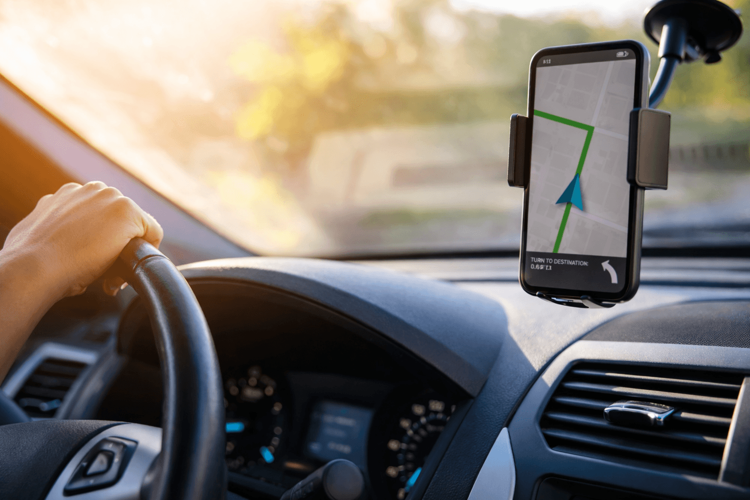 Driver using a phone mount with GPS navigation inside a car.