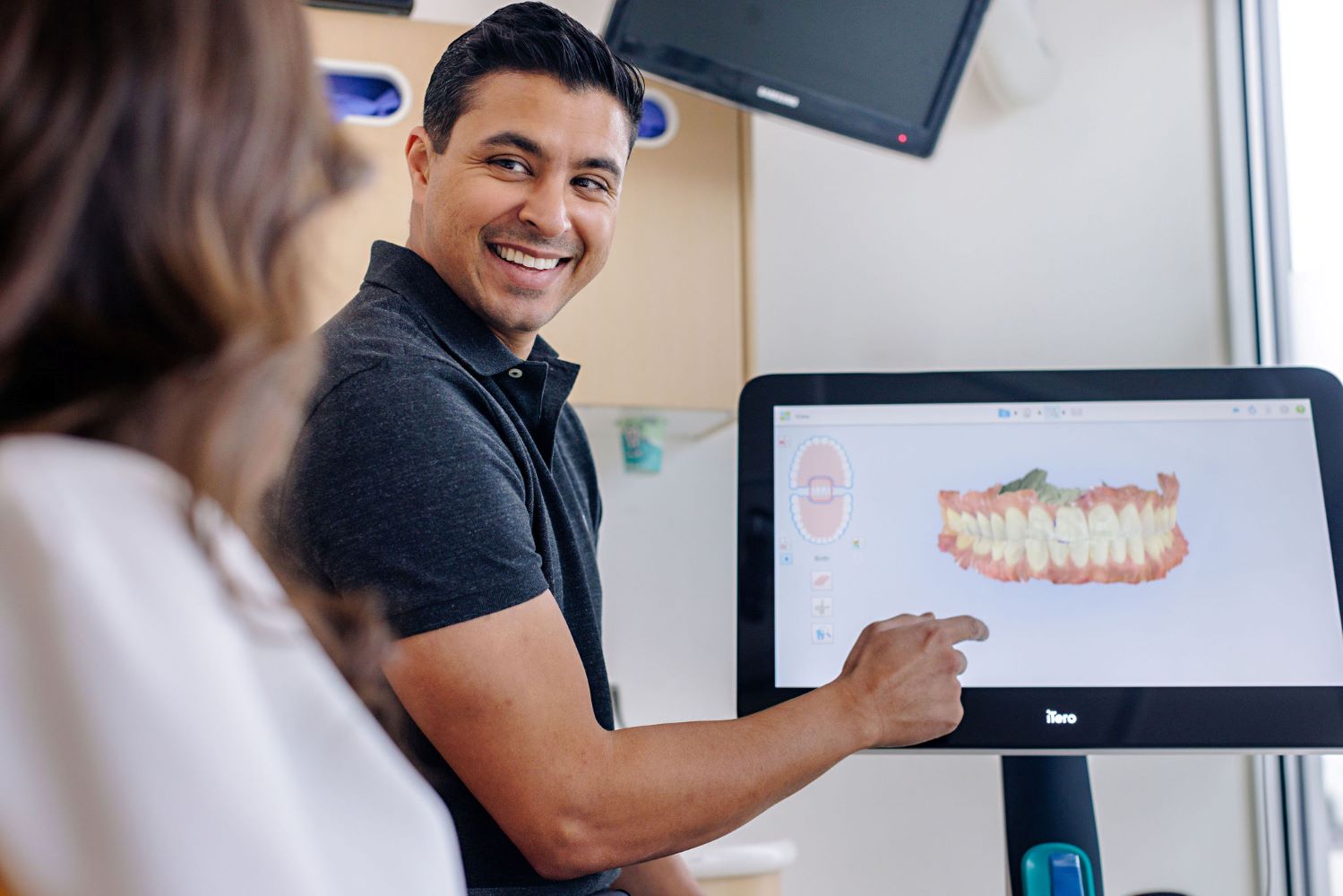 Dr.Kal showing a digital dental scan to a patient on a monitor.