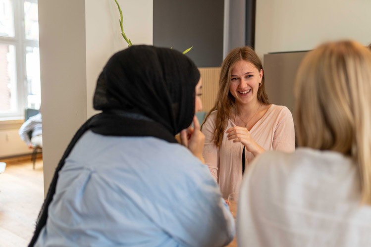 Drei Mitarbeiterinnen stehen im Kreis und unterhalten sich in einem modernen Besprechungsraum von SLB.