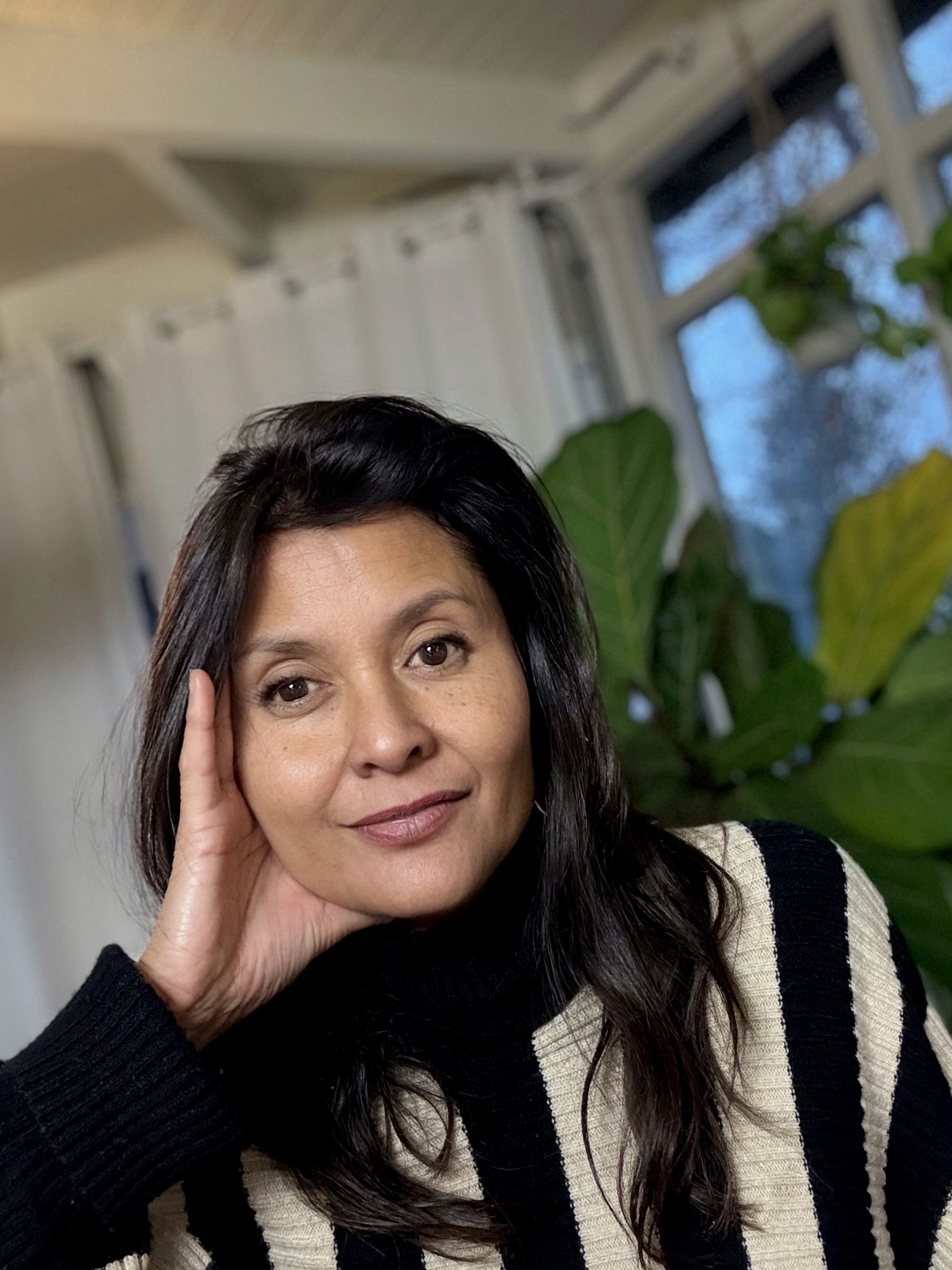 woman holding teacup while standing near window inside room during daytime