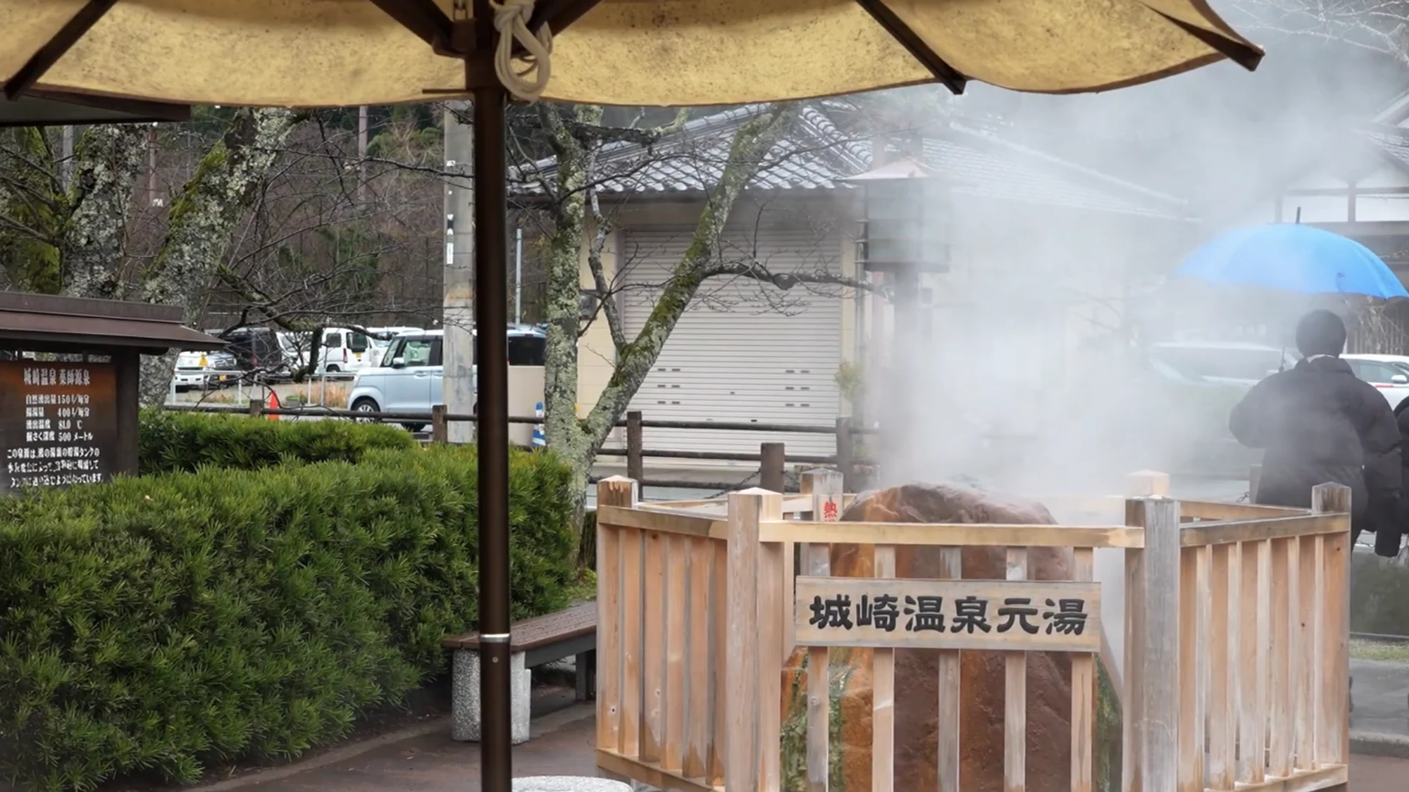 The Motoyu marker stone at the Kinosaki hot spring source, steam drifting behind it.
