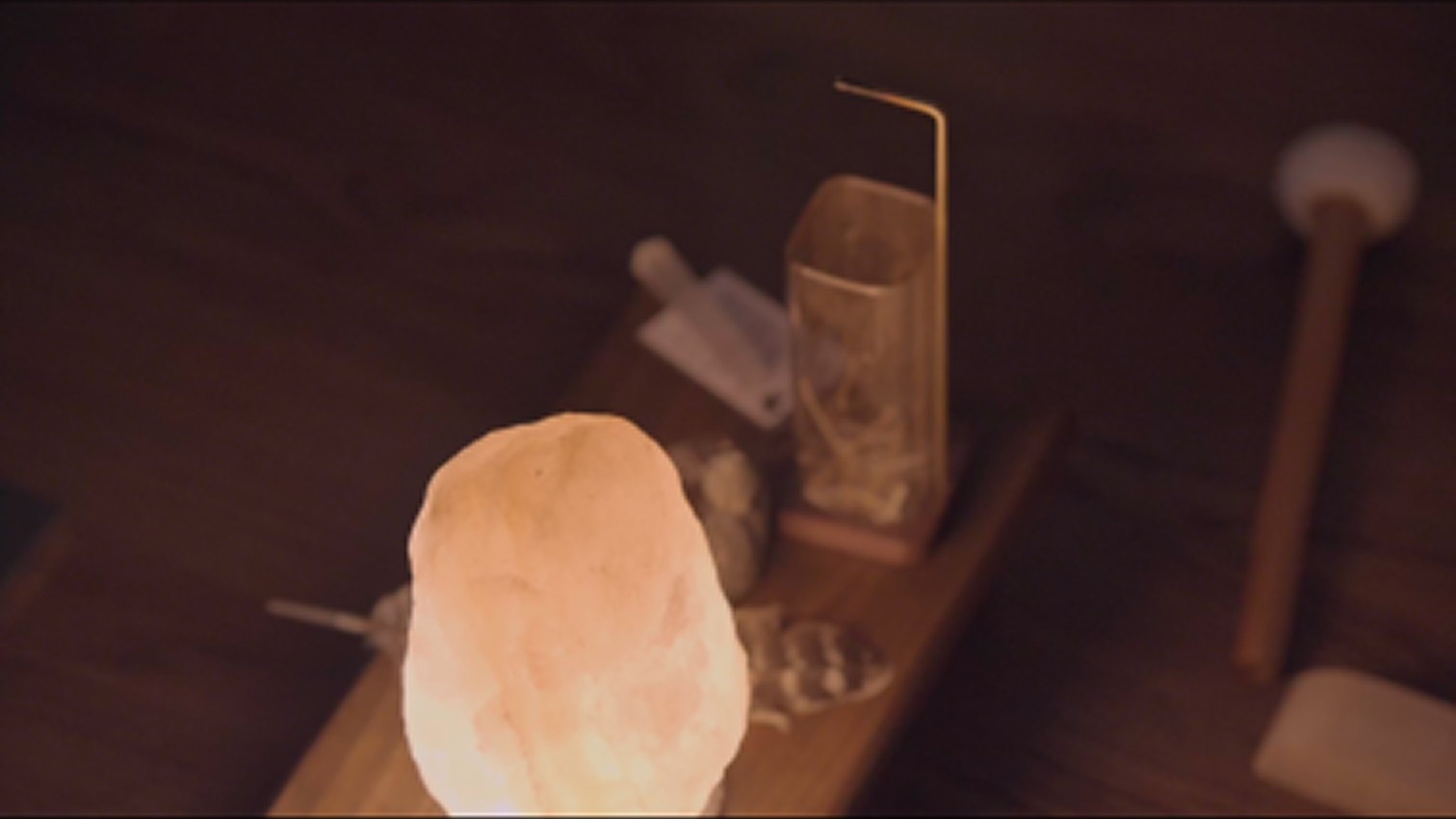 Pink Himalayan salt lamp on wooden board with kitchen utensils