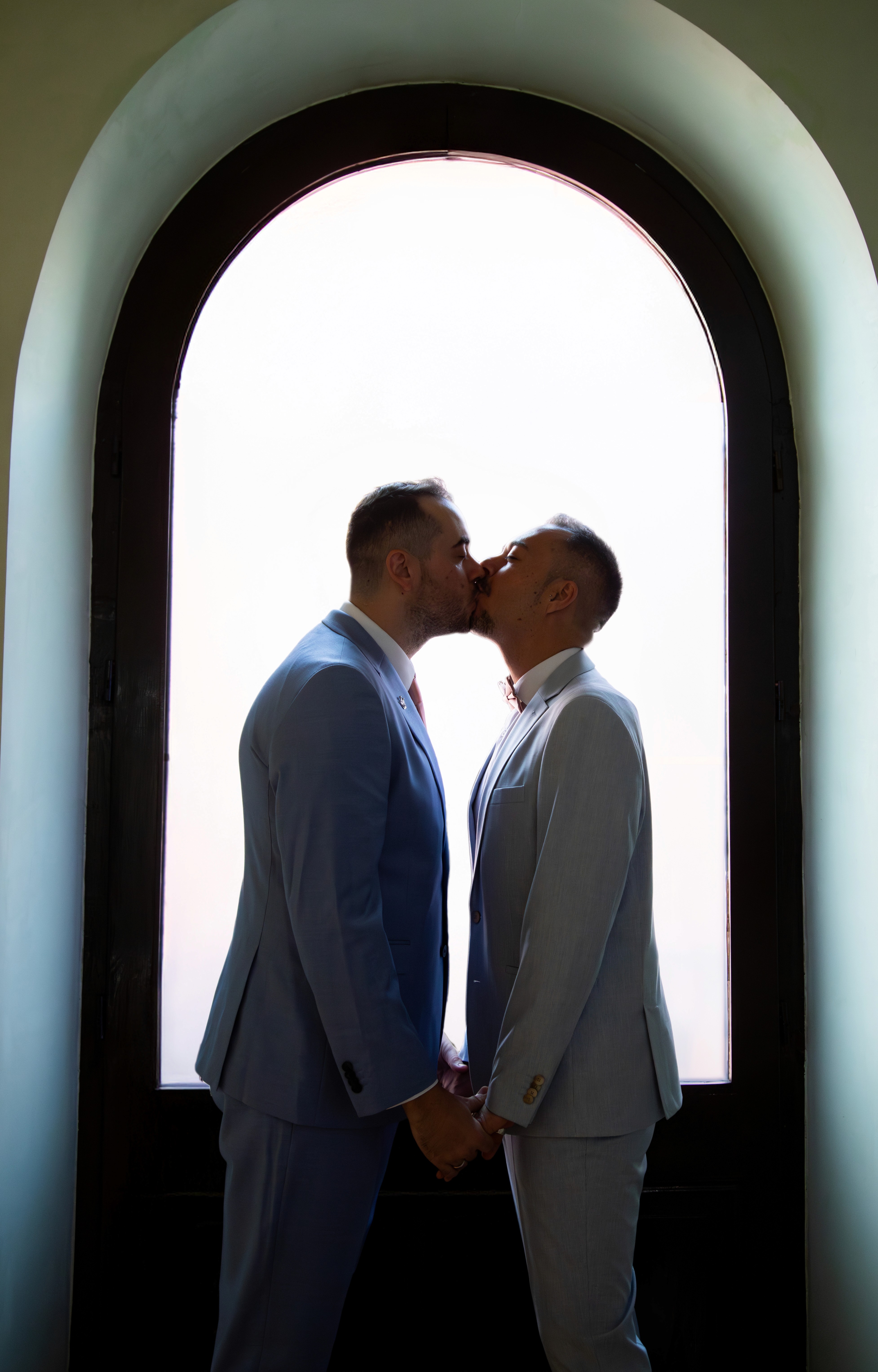 Sesión de boda. Pareja en una ventana dandose un beso