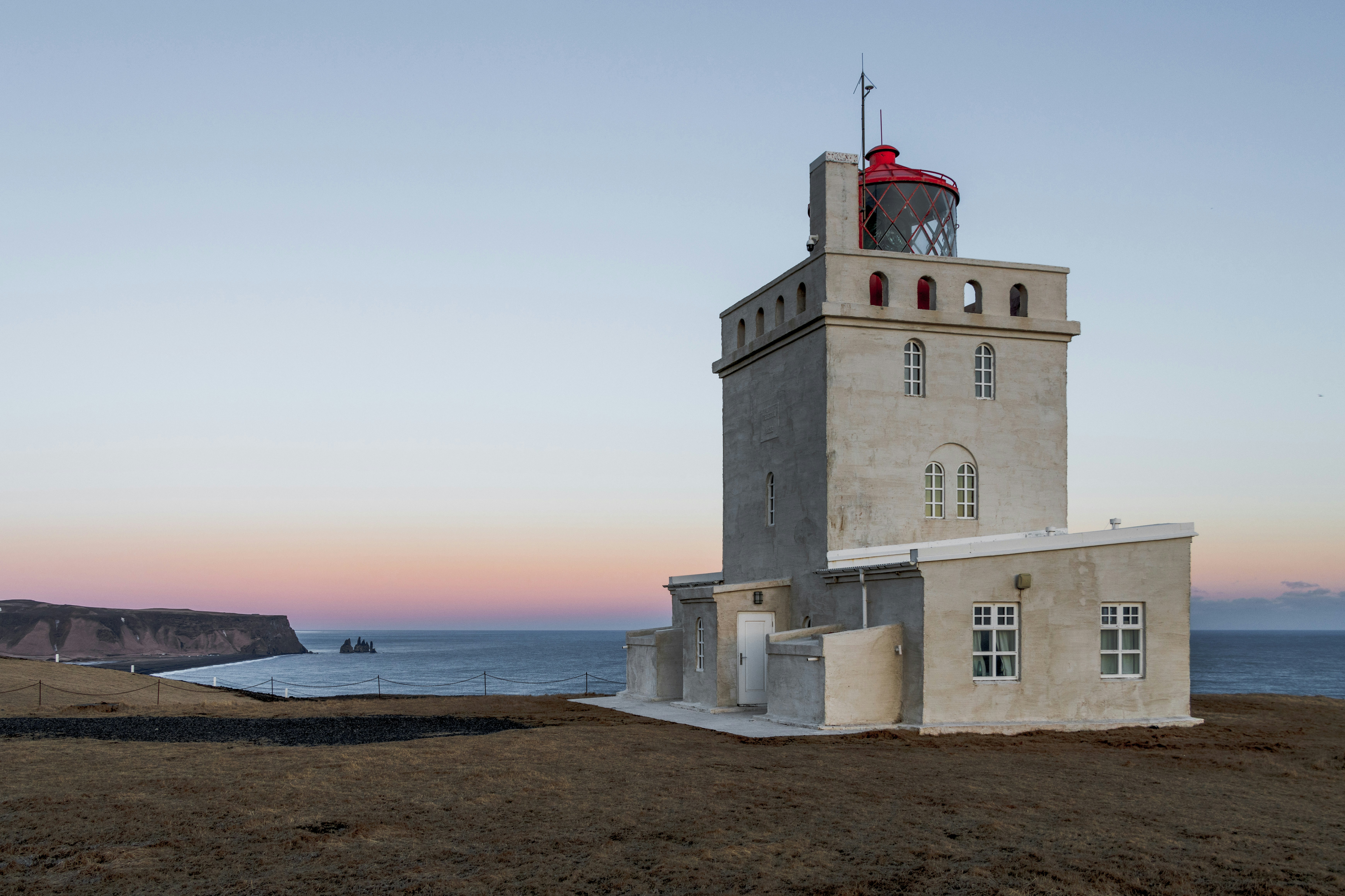 Dyrhólaey Lighthouse under a soft pink sky on Iceland’s South Coast.