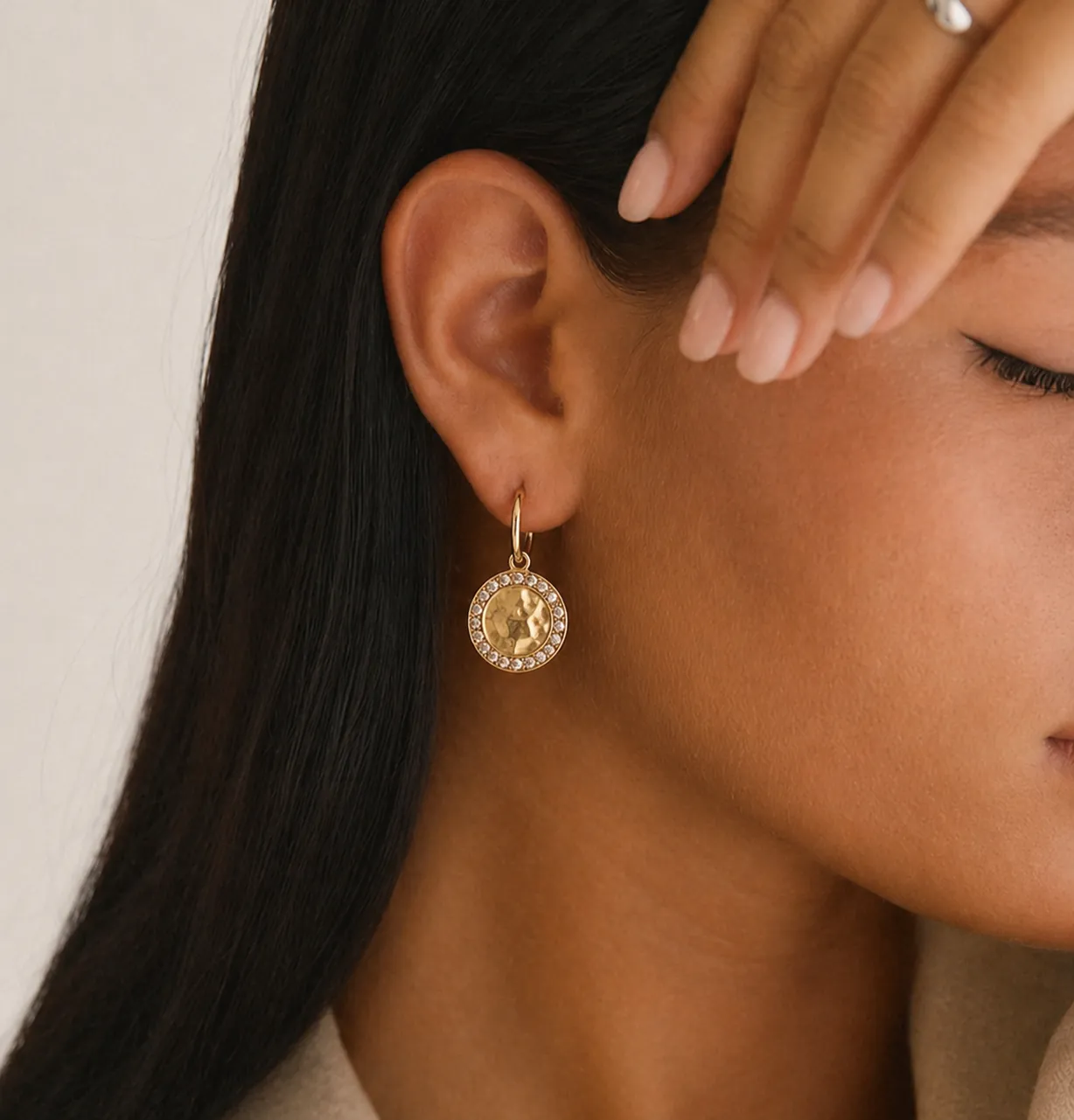 A close-up image of an individual showcasing a gold earring with a circular, intricate design, elegantly accentuating the ear, ideal for a jewelry website template.