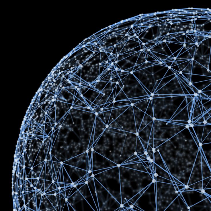 Smiling young man with curly hair, wearing a dark hoodie, against a softly lit background.