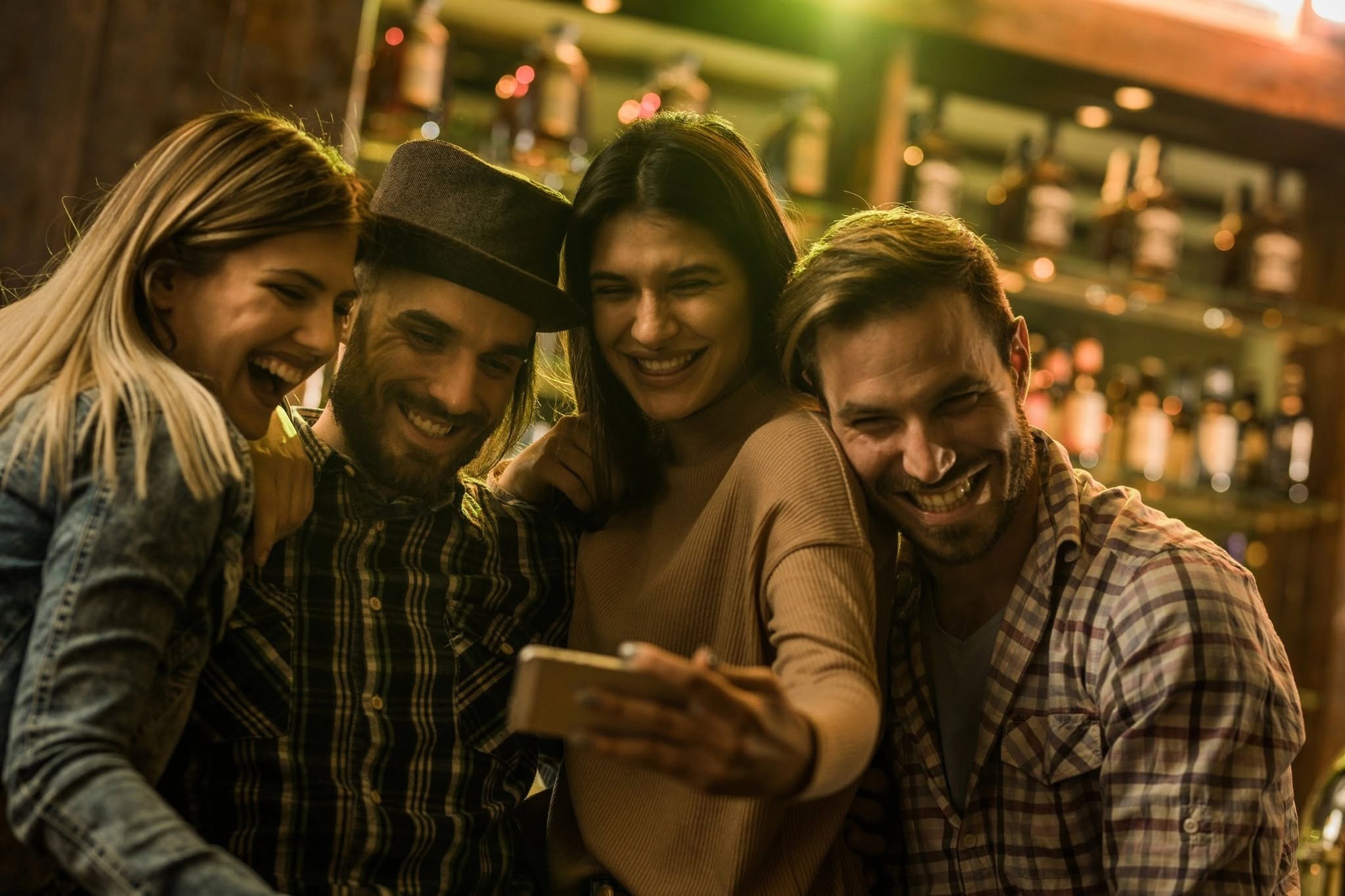 Group of friends smiling while taking a selfie at a restaurant.