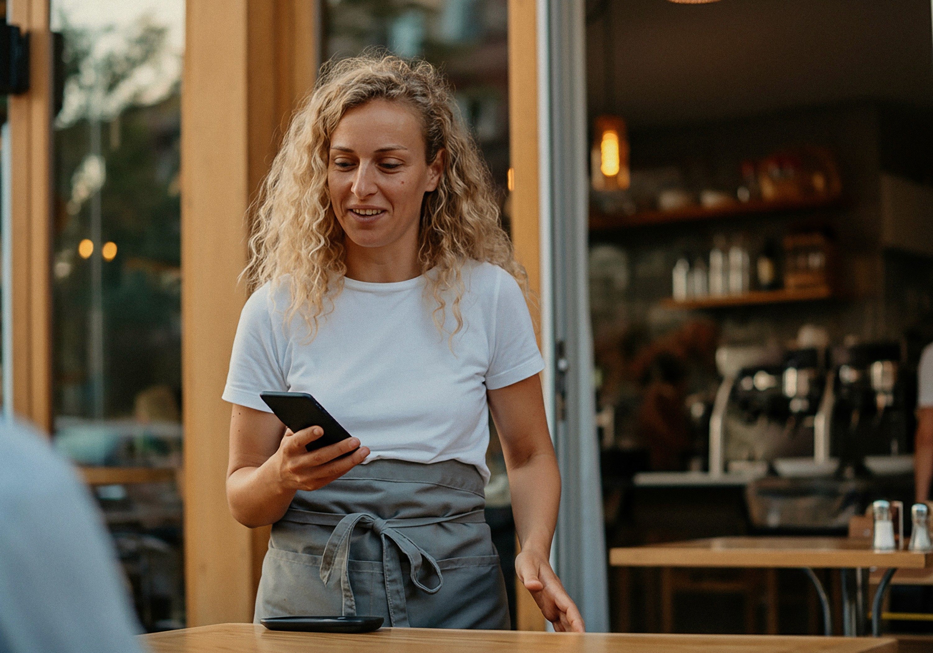 Barista handing a coffee to customers in a cosy cafe