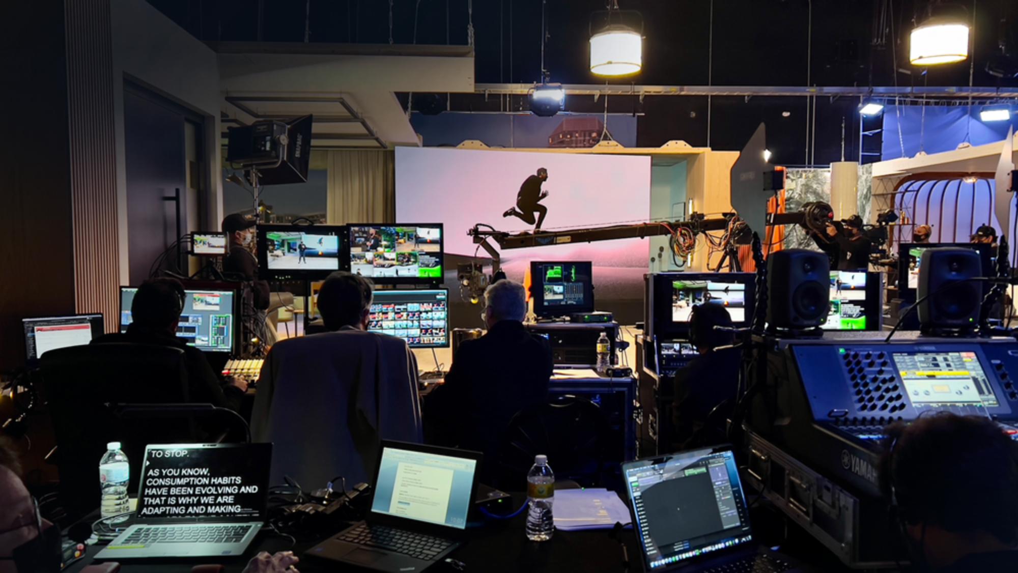 Corporate event control room with multiple monitors, camera crane, and production team managing a live studio recording.